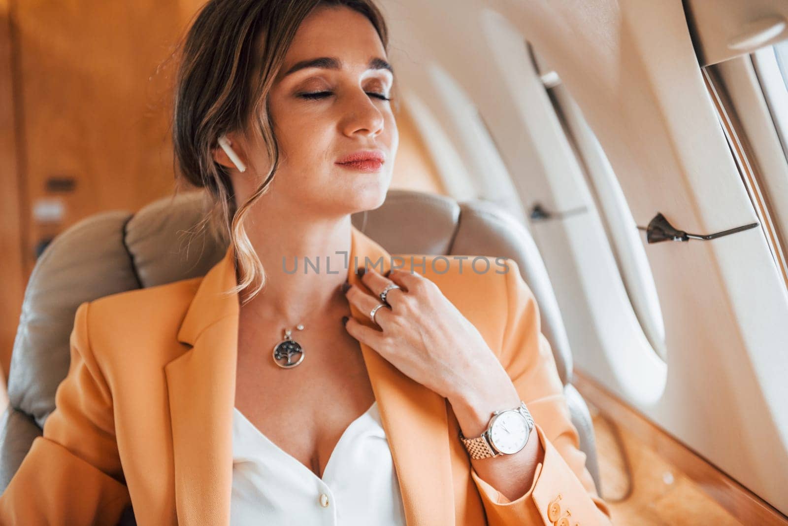 Young passenger woman in yellow clothes is flying in the plane by Standret