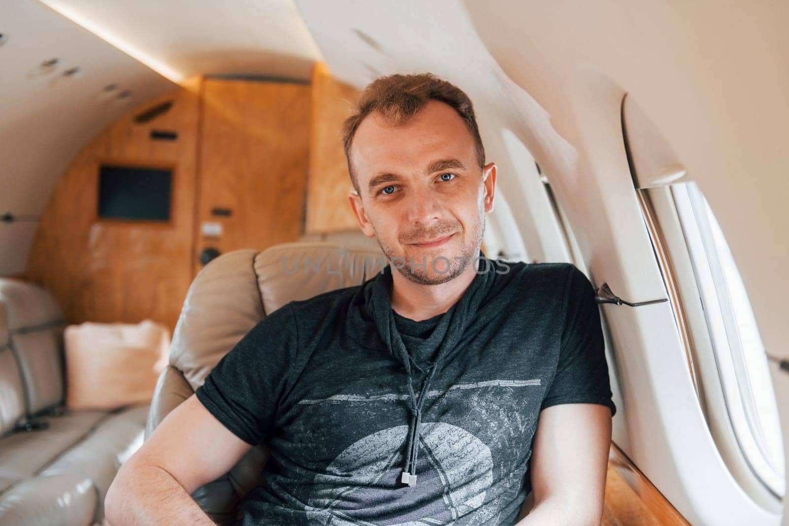 Man in casual clothes sitting indoors of passenger plane.