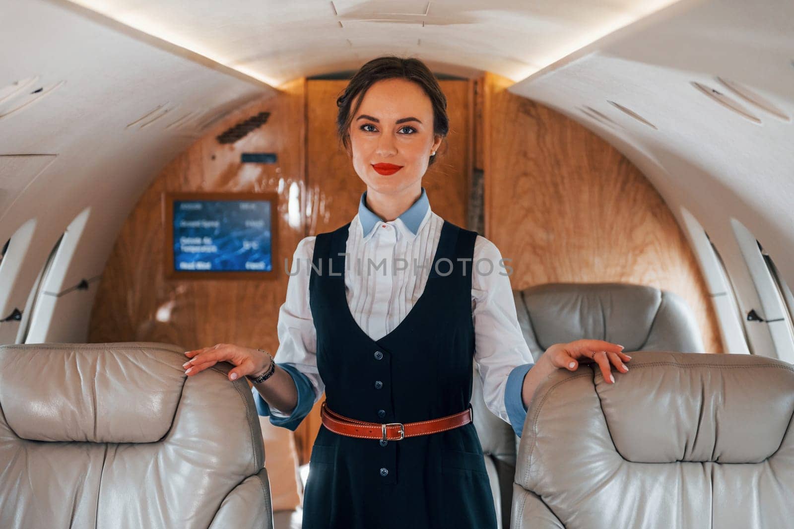 Young stewardess on the work in the passanger airplane by Standret