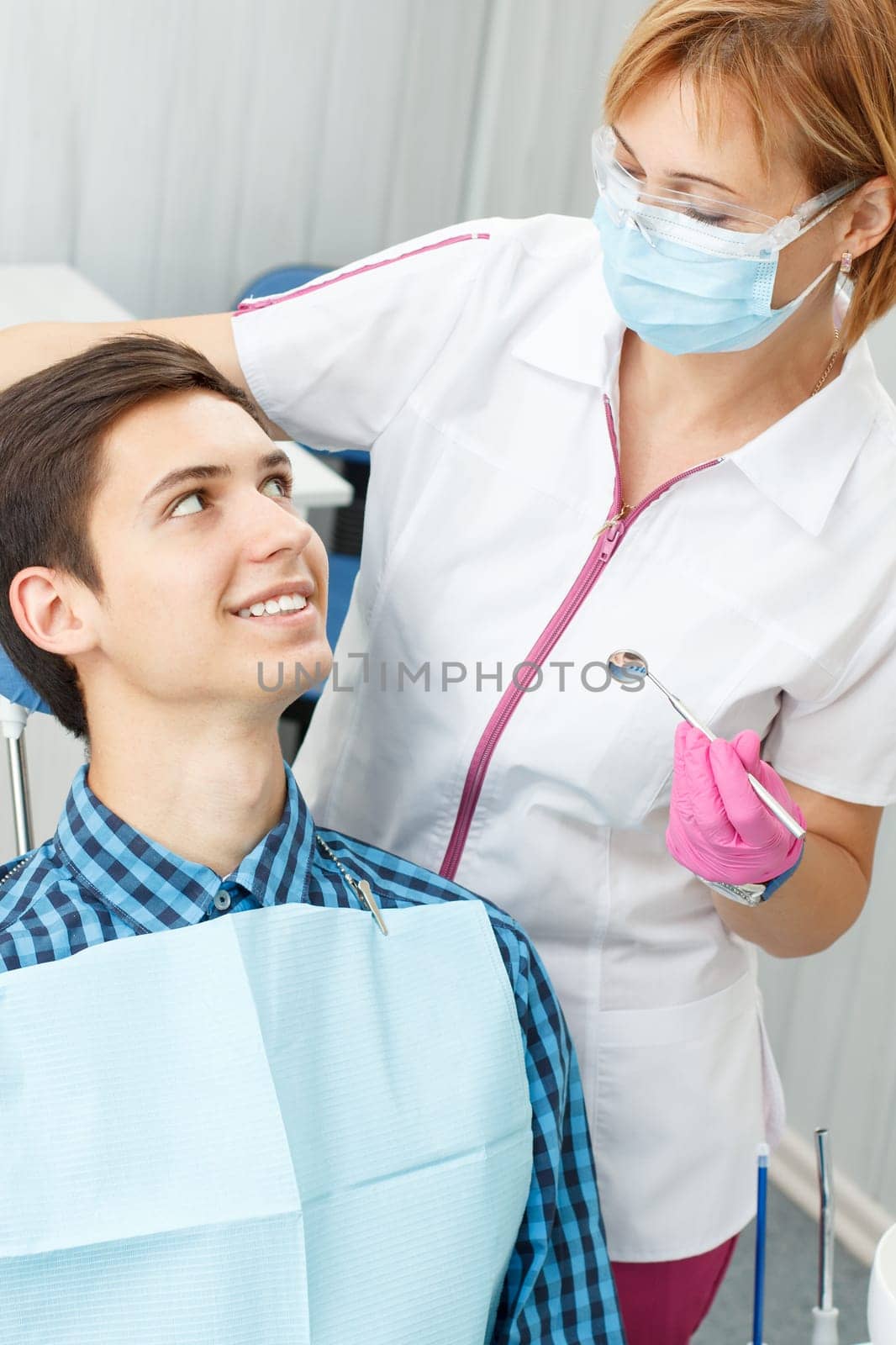Female dentist and young man in dentist office by mvg6894
