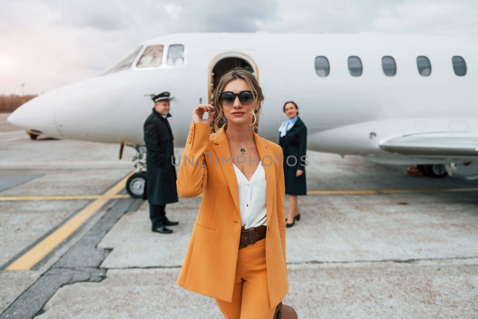 A young woman in yellow clothes is accompanied by an airline workers by Standret