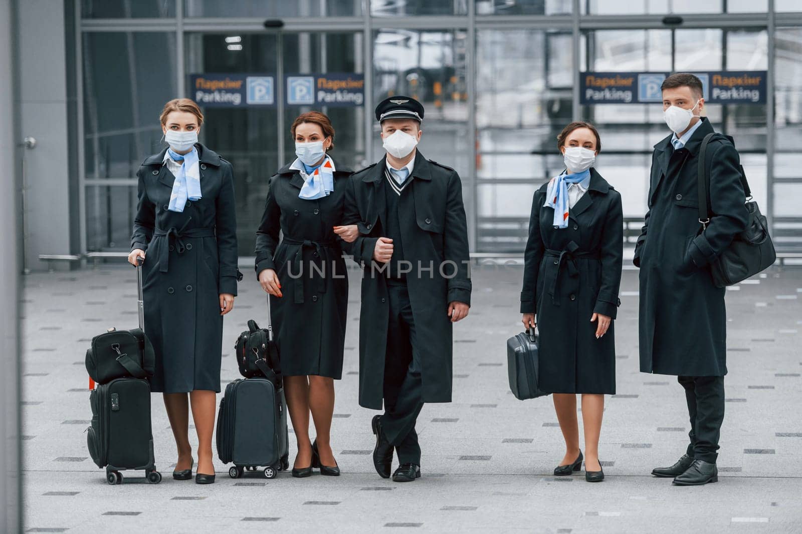 Aircraft crew in work uniform is together outdoors in the airport by Standret