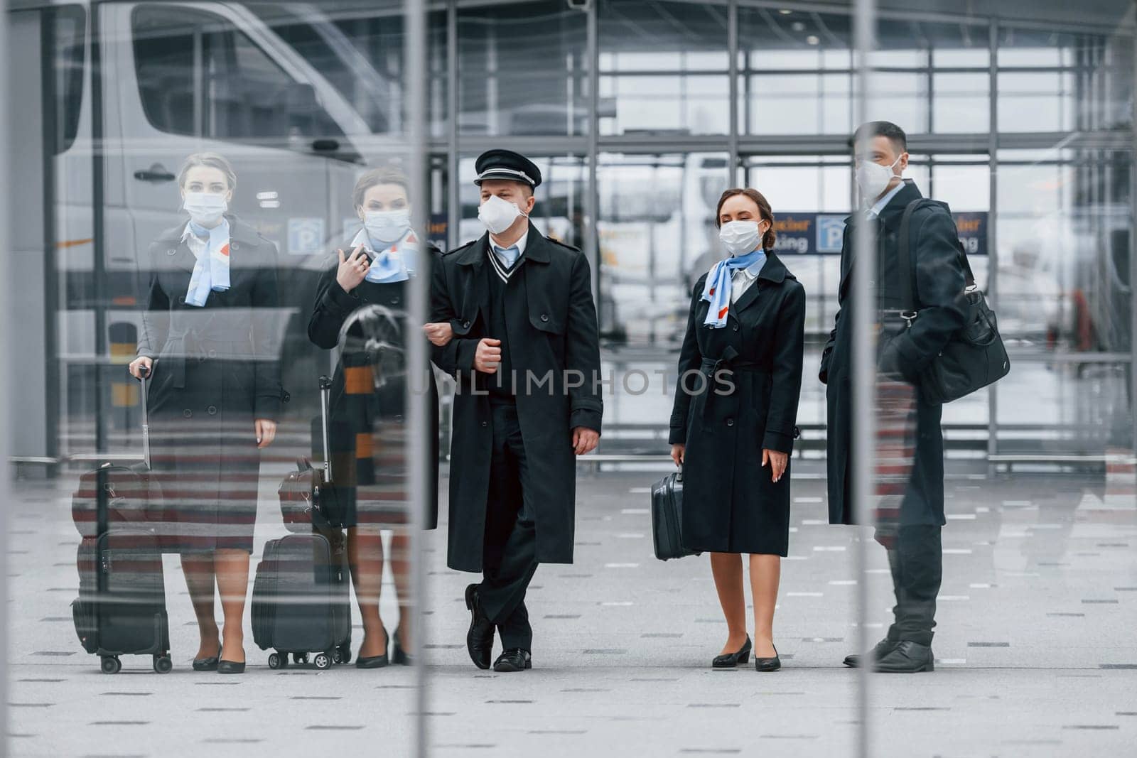 Aircraft crew in work uniform is together outdoors in the airport.