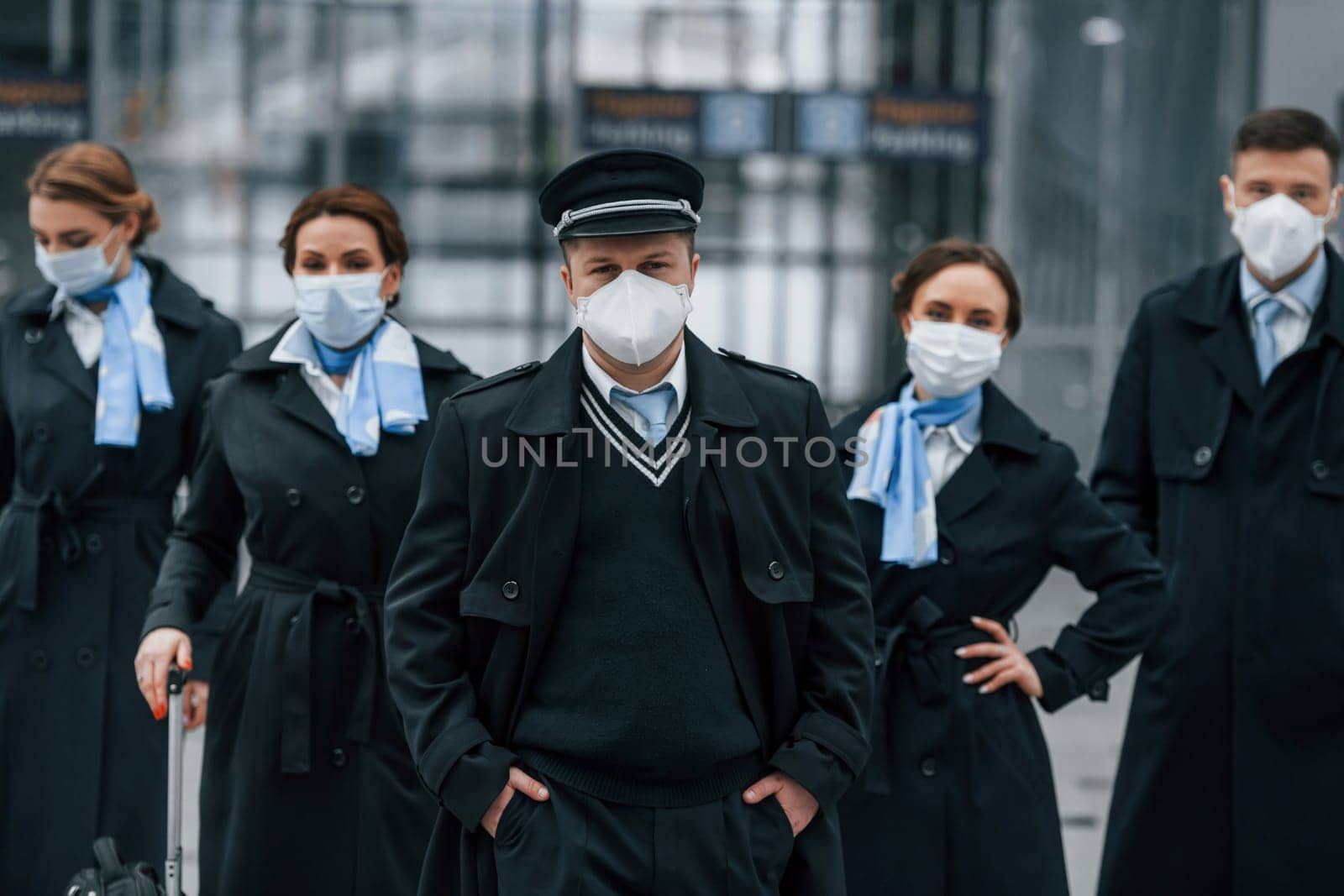 Aircraft crew in work uniform is together outdoors in the airport by Standret