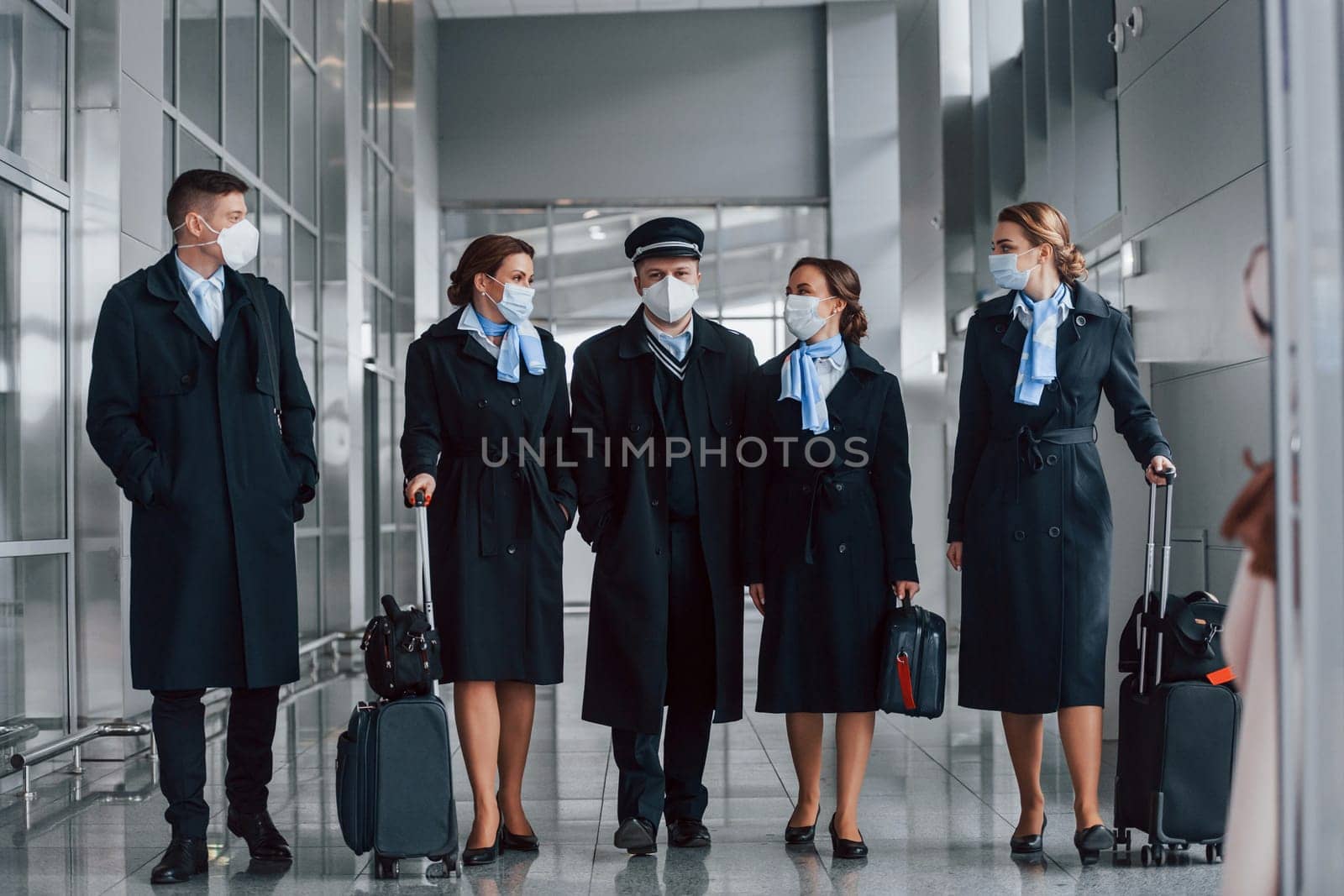 Aircraft crew in work uniform is together outdoors in the airport by Standret