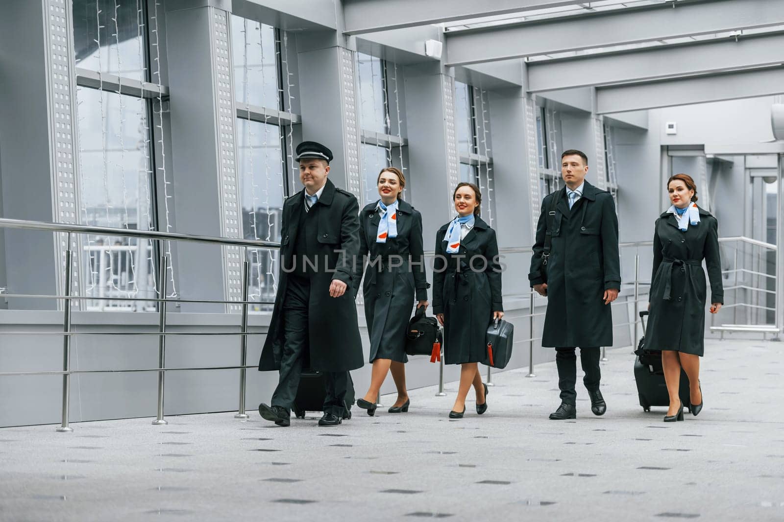 Aircraft crew in work uniform is together outdoors in the airport by Standret