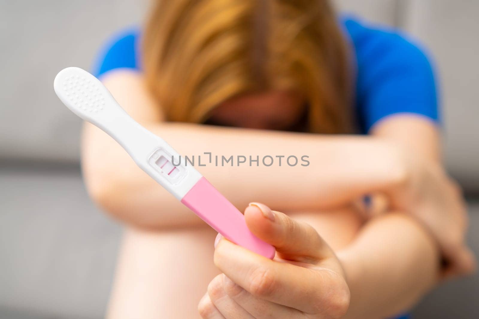Disappointed woman holding a positive pregnancy test by vladimka