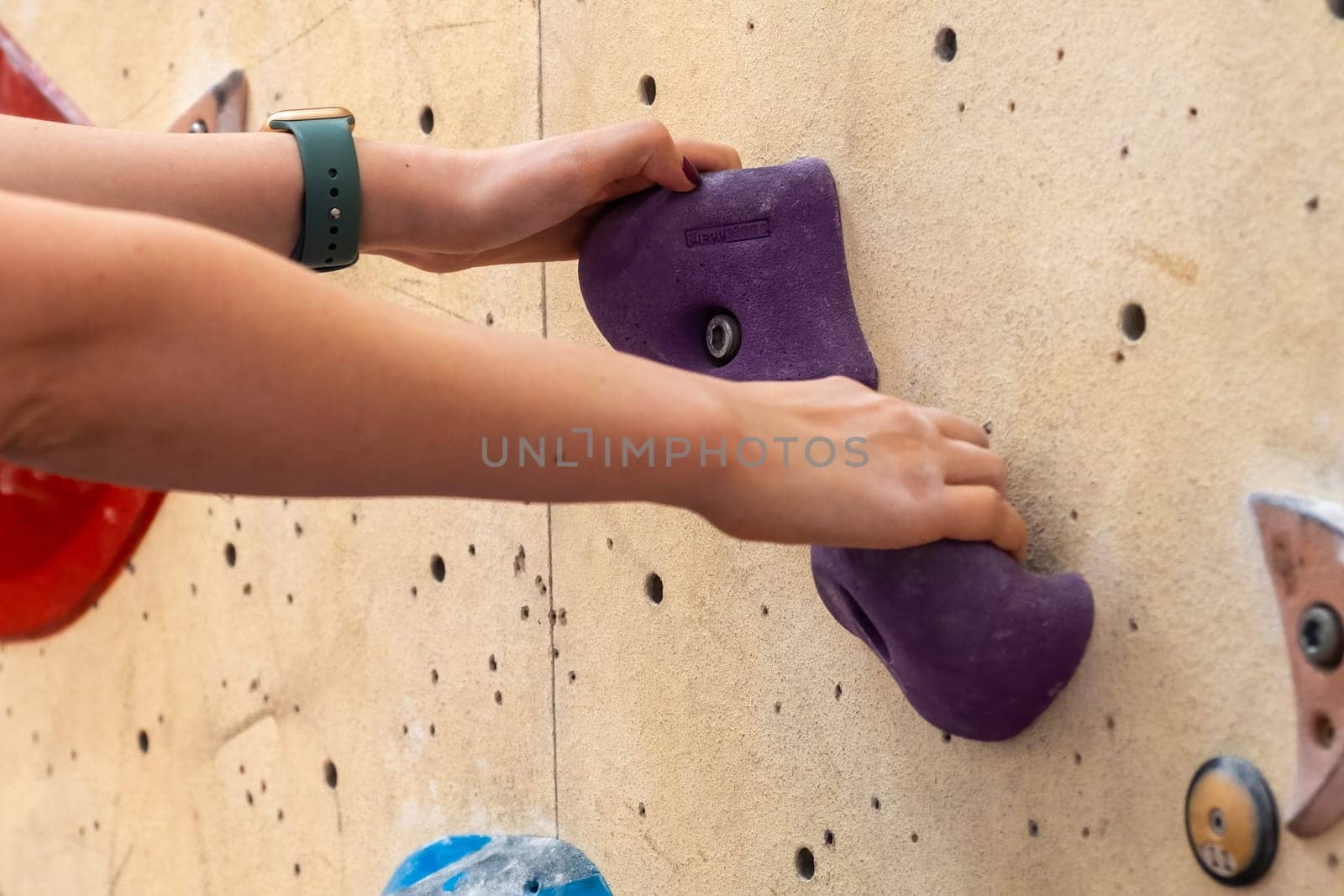 Close up mountaineer holding grips on climbing artificial rock.