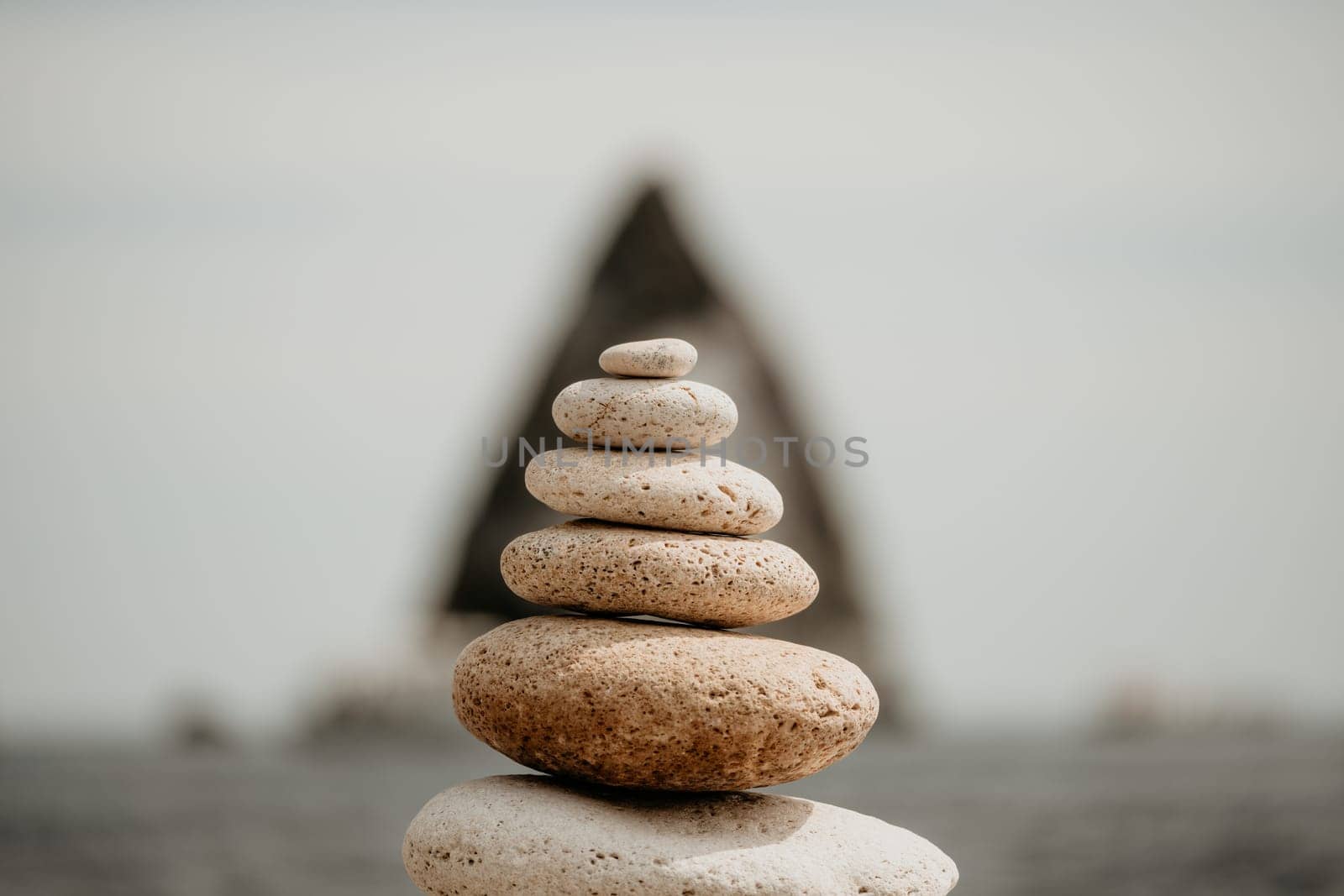 Pyramid stones on the seashore with warm sunset on the sea background. Happy holidays. Pebble beach, calm sea, travel destination. Concept of happy vacation on the sea, meditation, spa, calmness.