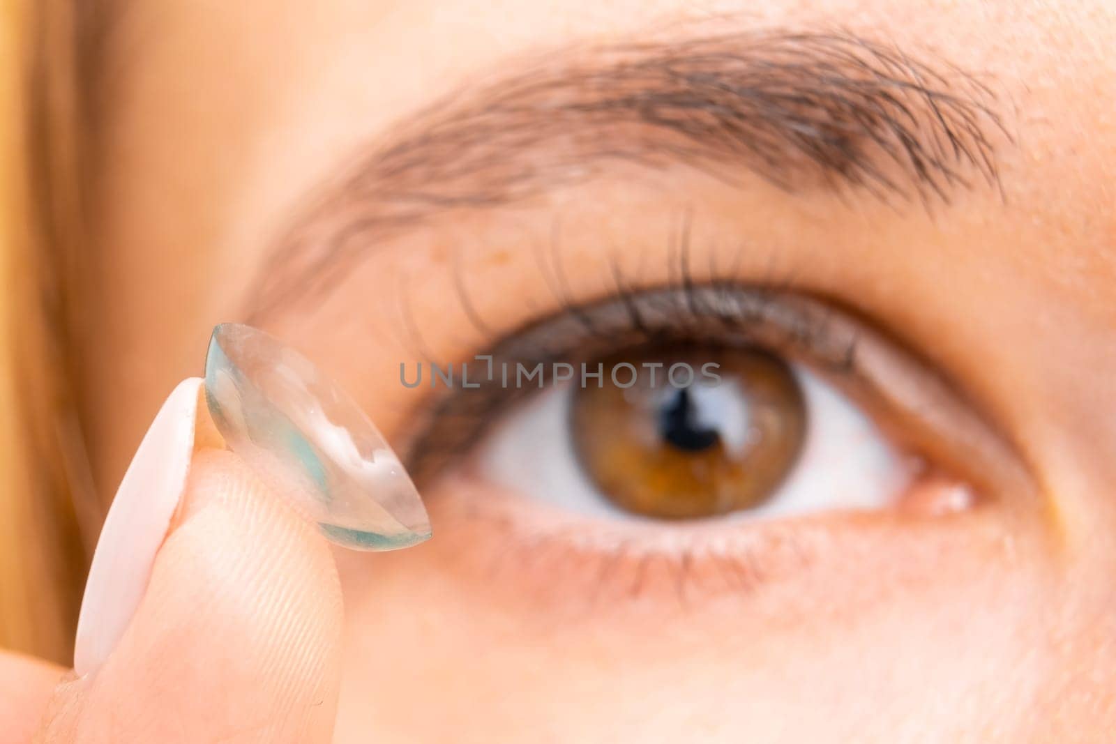 Contact lens for improvement of vision, closeup to female brown eye.