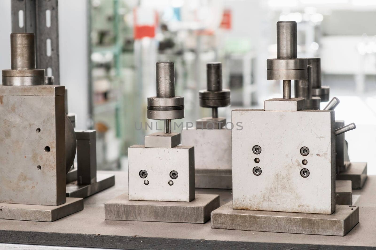 Machine tool with shining metal cylinders in brightly lit workshop of contemporary manufacturing plant extreme close view