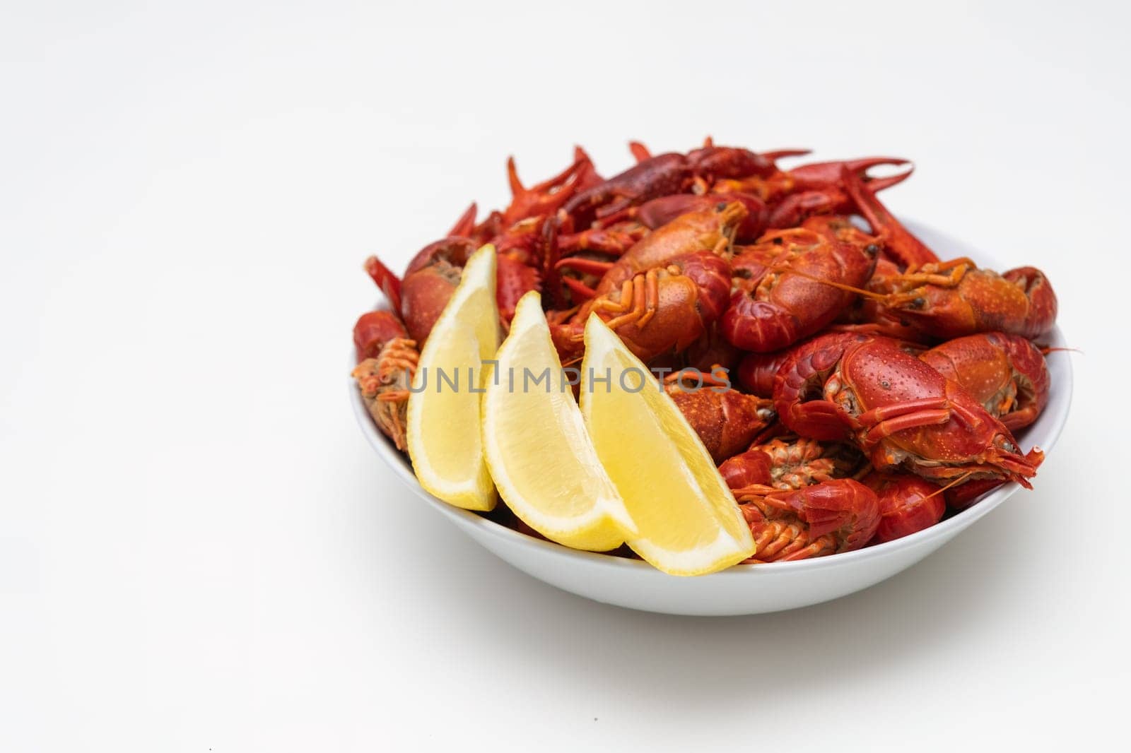 Fresh red boiled crayfish food on a plate on a white background. Healthy seafood snack with lemon.