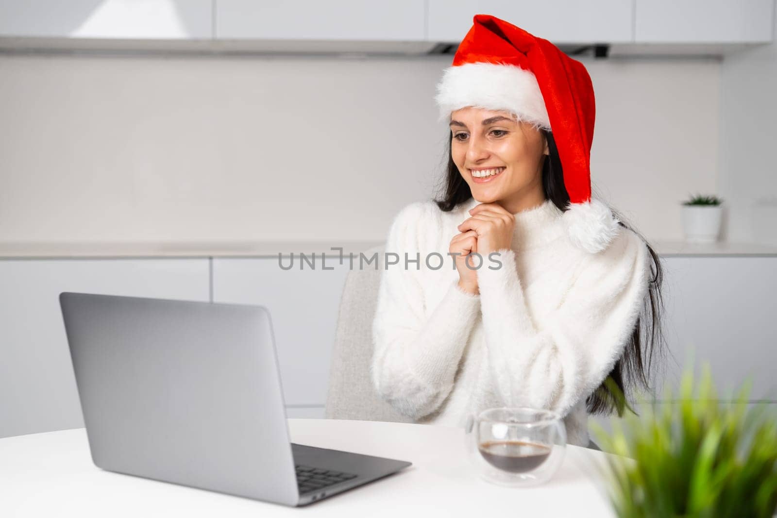 Smiling woman wearing a Santa Claus hat having a video call with friends or family on Christmas. by vladimka