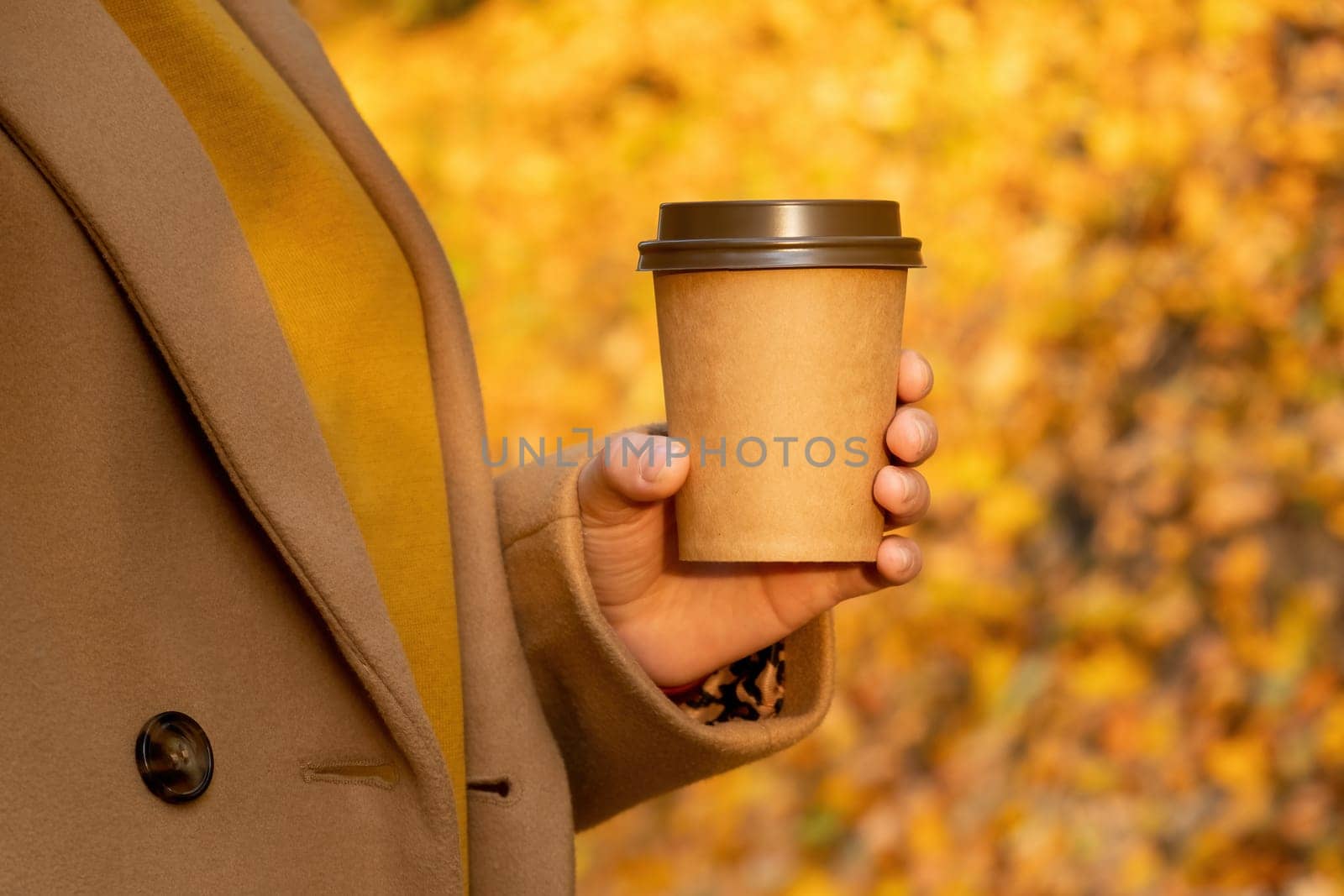 Close up woman holding a cup of coffee against fall forest. by vladimka