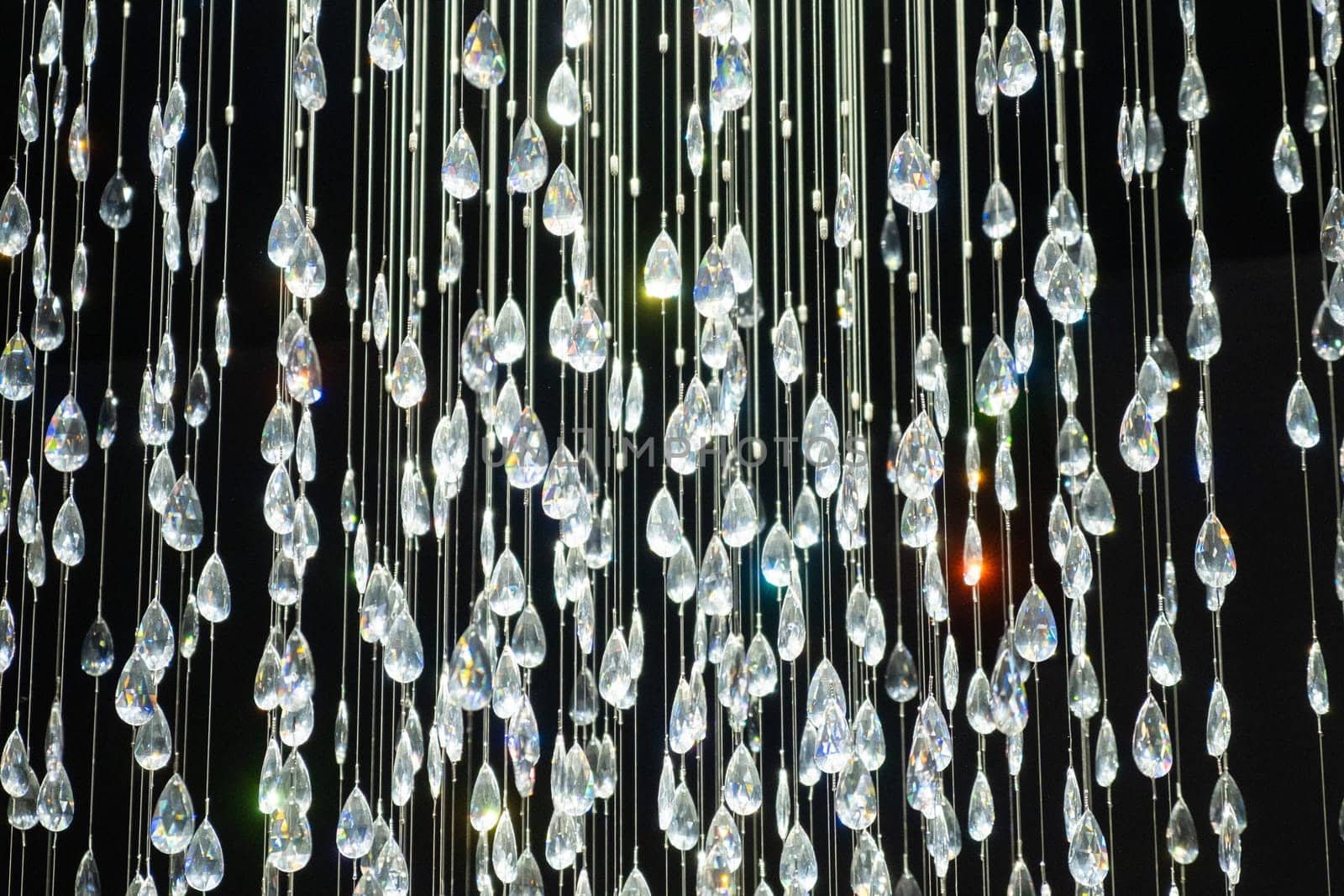 Crystal stones dangle and glisten on black background. Shining crystal chandelier.