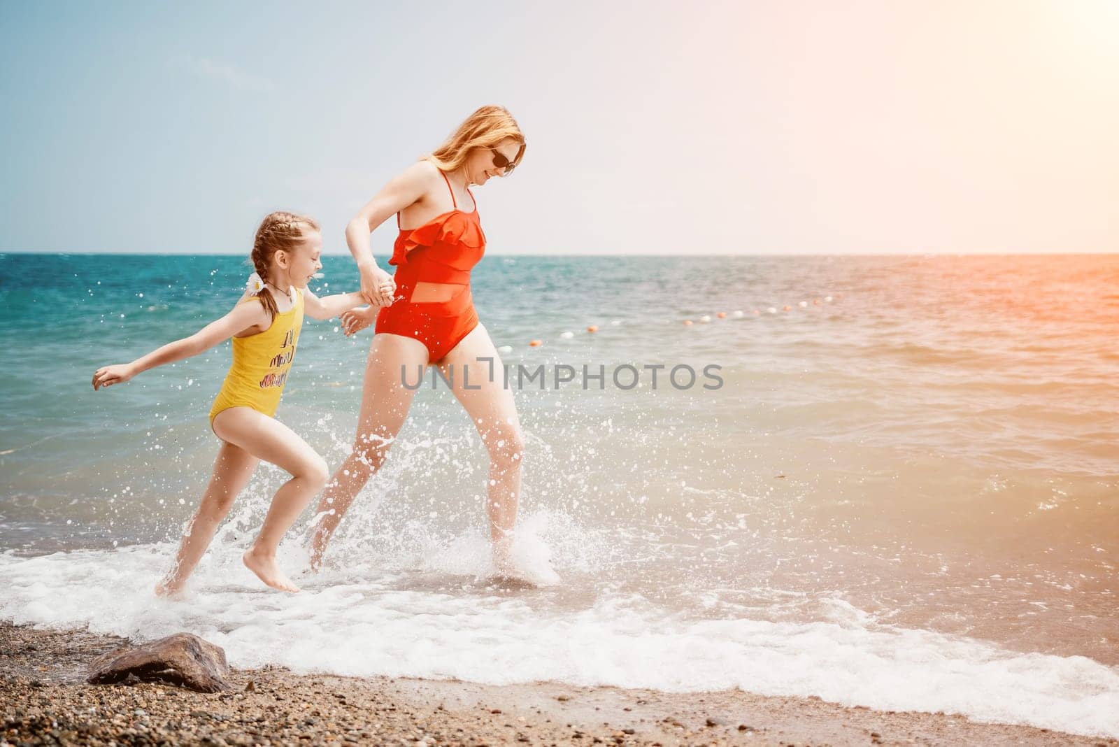 Happy loving family mother and daughter having fun together on the beach. Mum playing with her kid in holiday vacation next to the ocean - Family lifestyle and love concept.