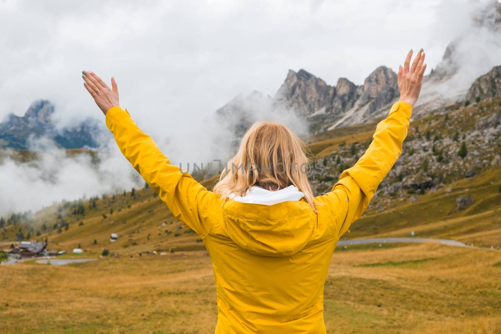 Happy woman spreads hands and sees Passo Giau pass in dense fog. by vladimka