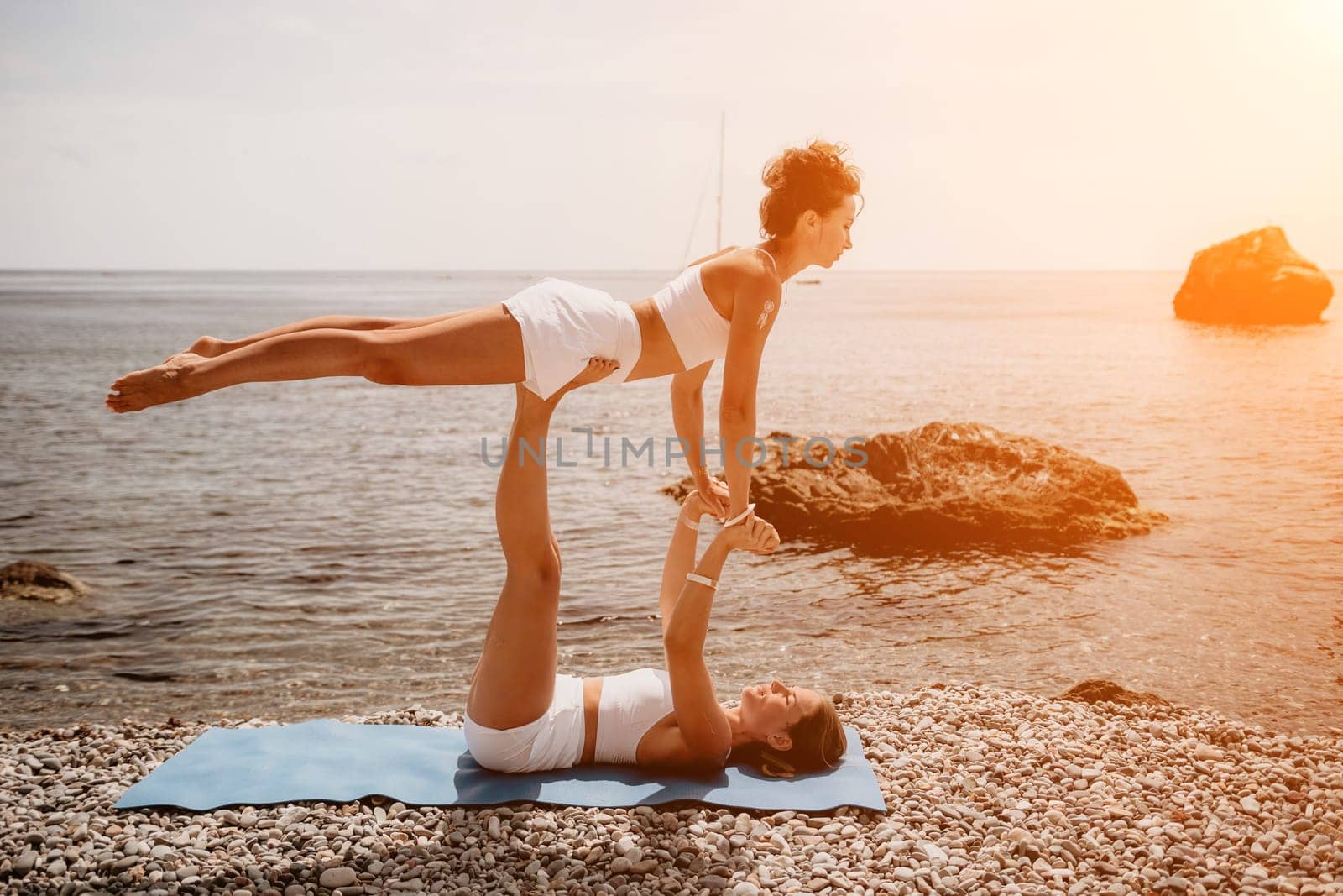 Woman sea yoga. Back view of free calm happy satisfied woman with long hair standing on top rock with yoga position against of sky by the sea. Healthy lifestyle outdoors in nature, fitness concept.