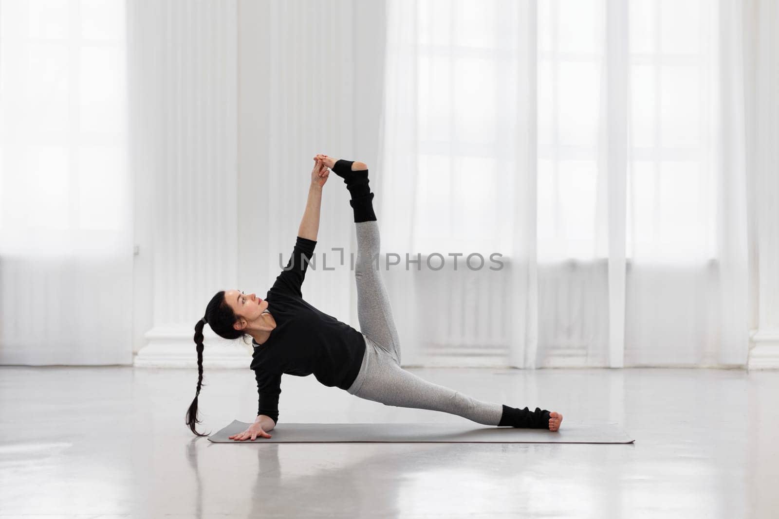 Young woman instructor doing vertical splits during yoga class in cozy living room. The concept of energy, strength and flexibility, as well as to get rid of tension, negativity and stress.