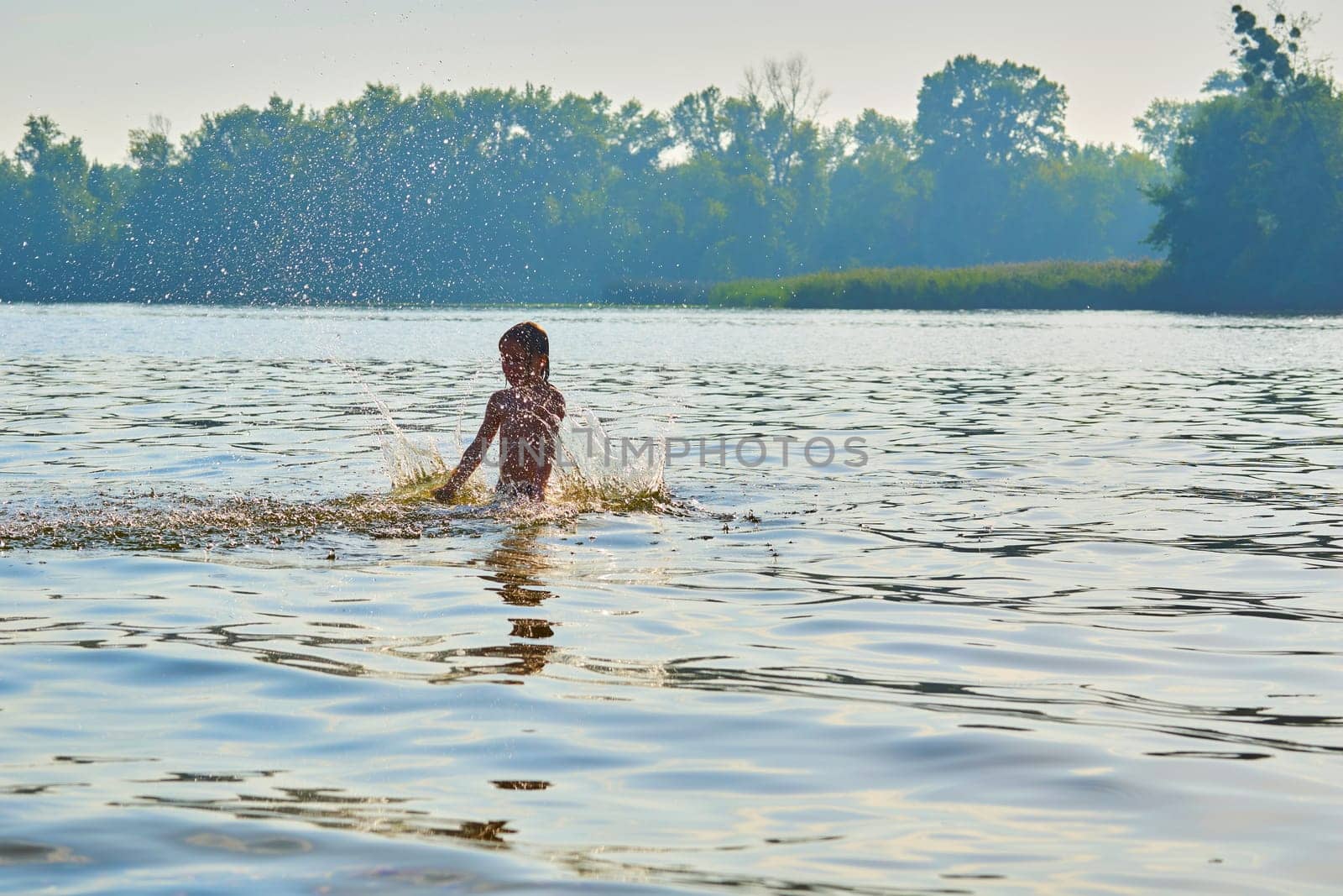 Pleased happy child bathes plays with splashes in a warm summer river, lake by jovani68