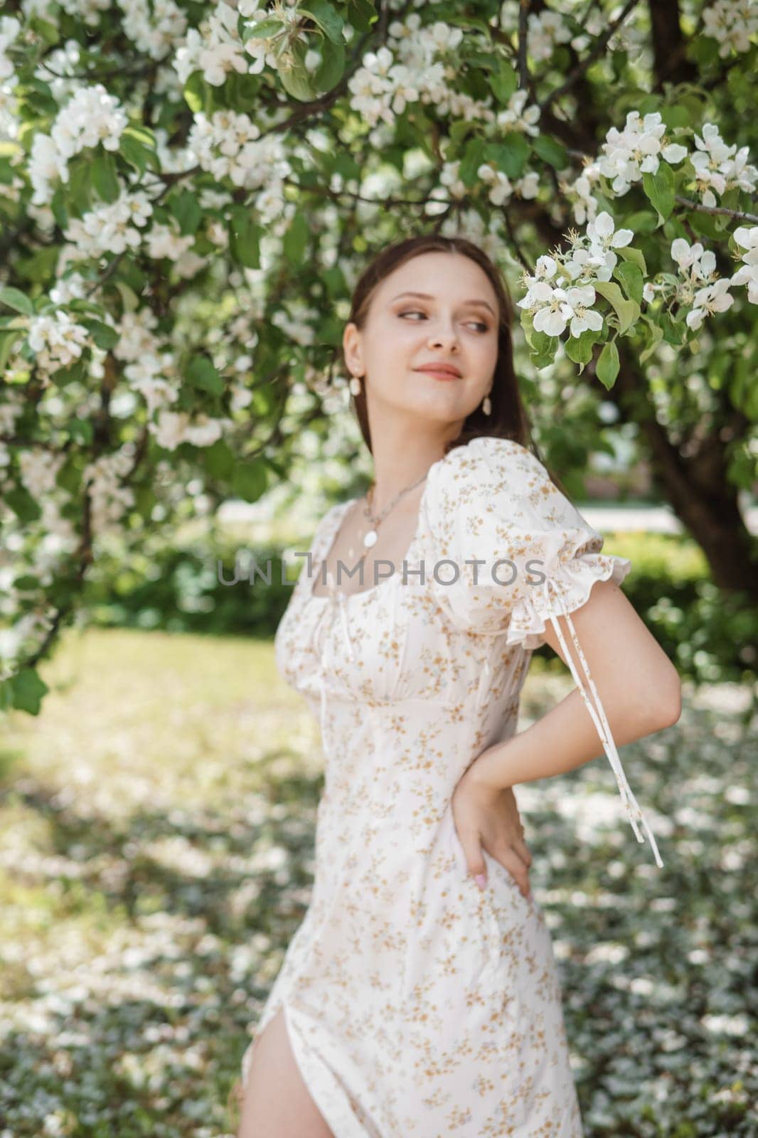 An attractive long-haired woman walks in the spring in the park of blooming apple trees. by Annu1tochka