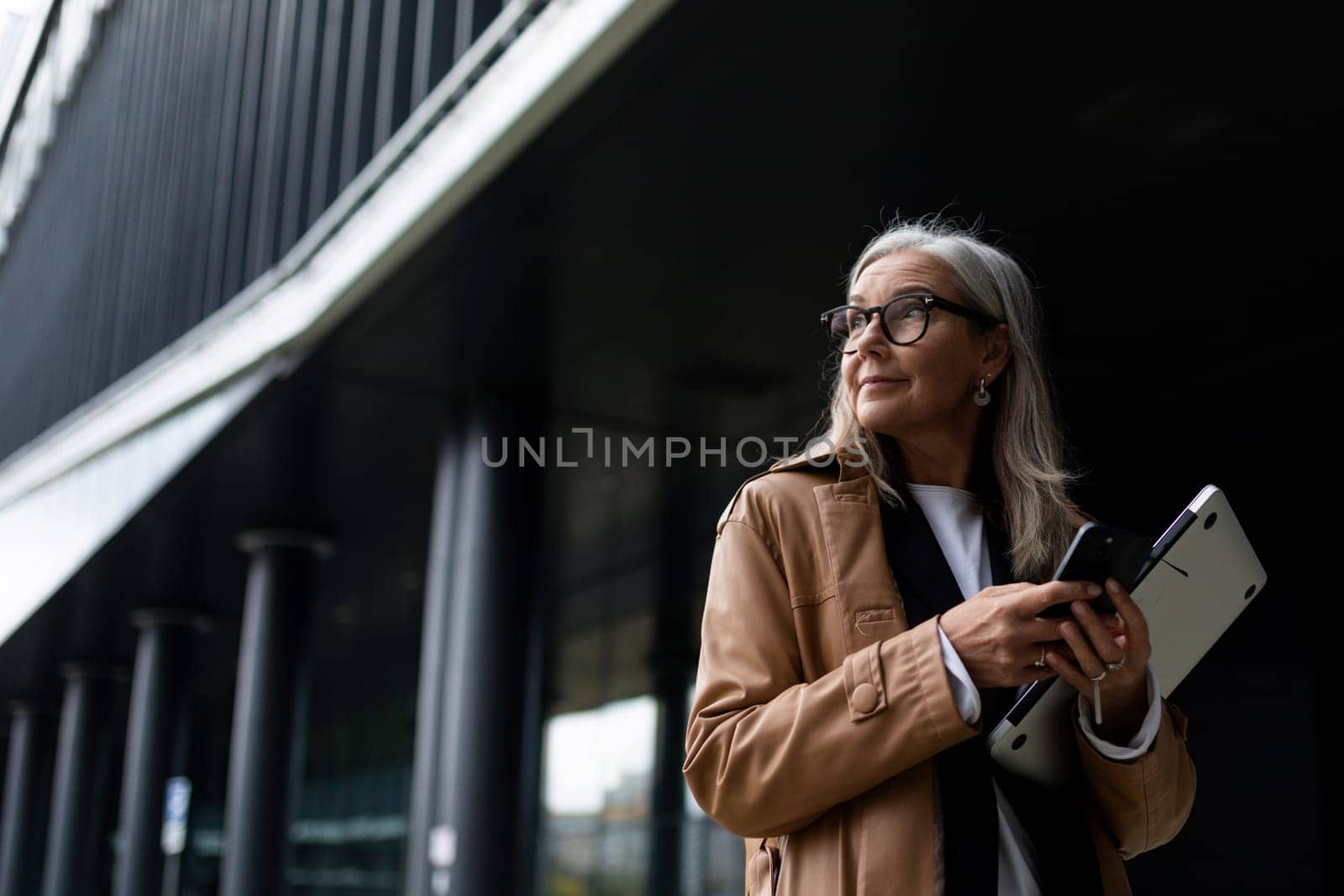 portrait of a successful stylish business elderly woman on the background of a modern office center, strong and independent woman concept by TRMK