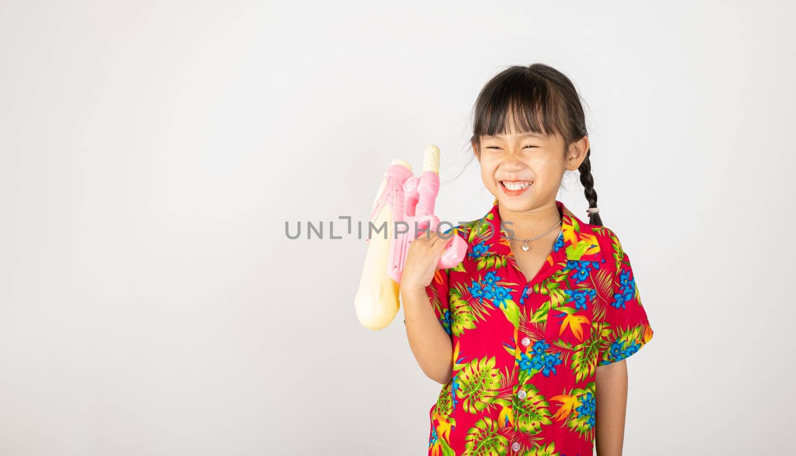 Happy Songkran Day, Asian kid girl with floral shirt hold water gun, Thai child funny hold toy water pistol and smile, isolated on white background, Thailand Songkran festival national culture concept