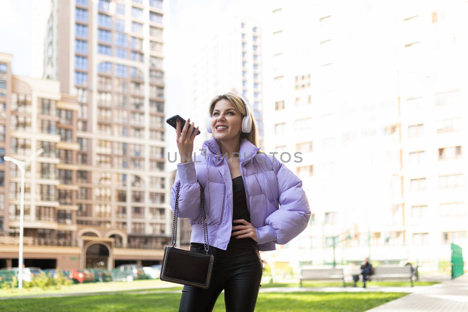 caucasian woman 40 years old in headphones speaks on a mobile phone hands-free outside.