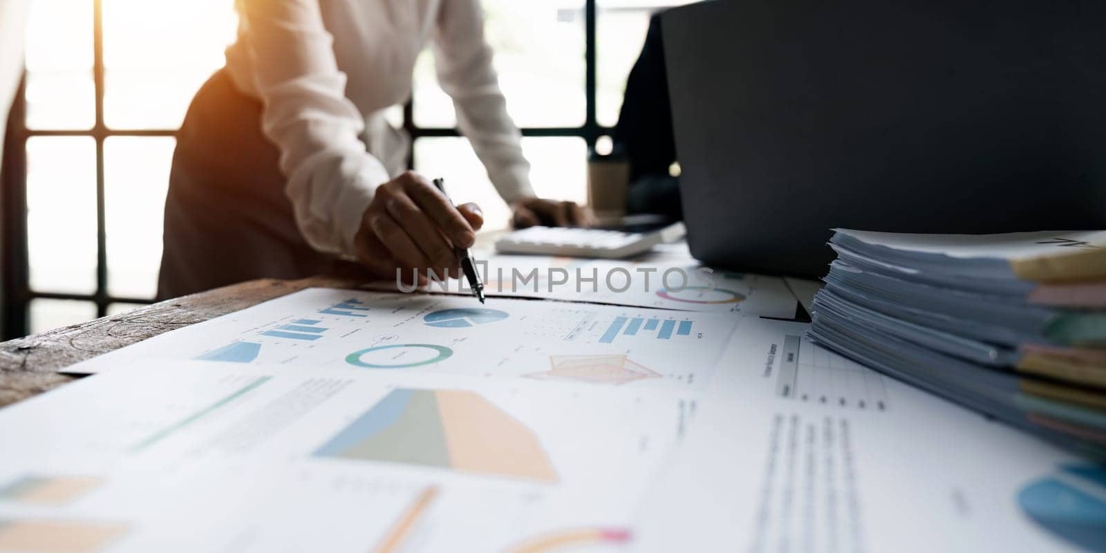 Accountant using a calculator to calculate numbers on a company's financial documents, analyzing historical financial data to plan how to grow the company. Financial concept.