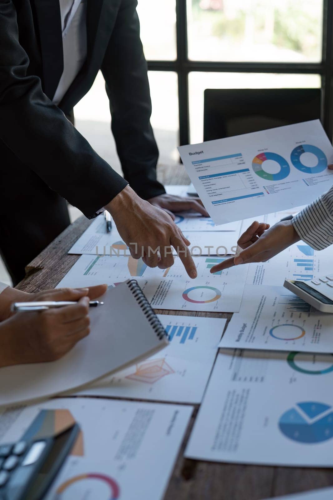 Diverse businesspeople cooperate work together discussing company financial statistics, multiracial colleagues employees collaborate brainstorm with finance document at meeting. close up shot.