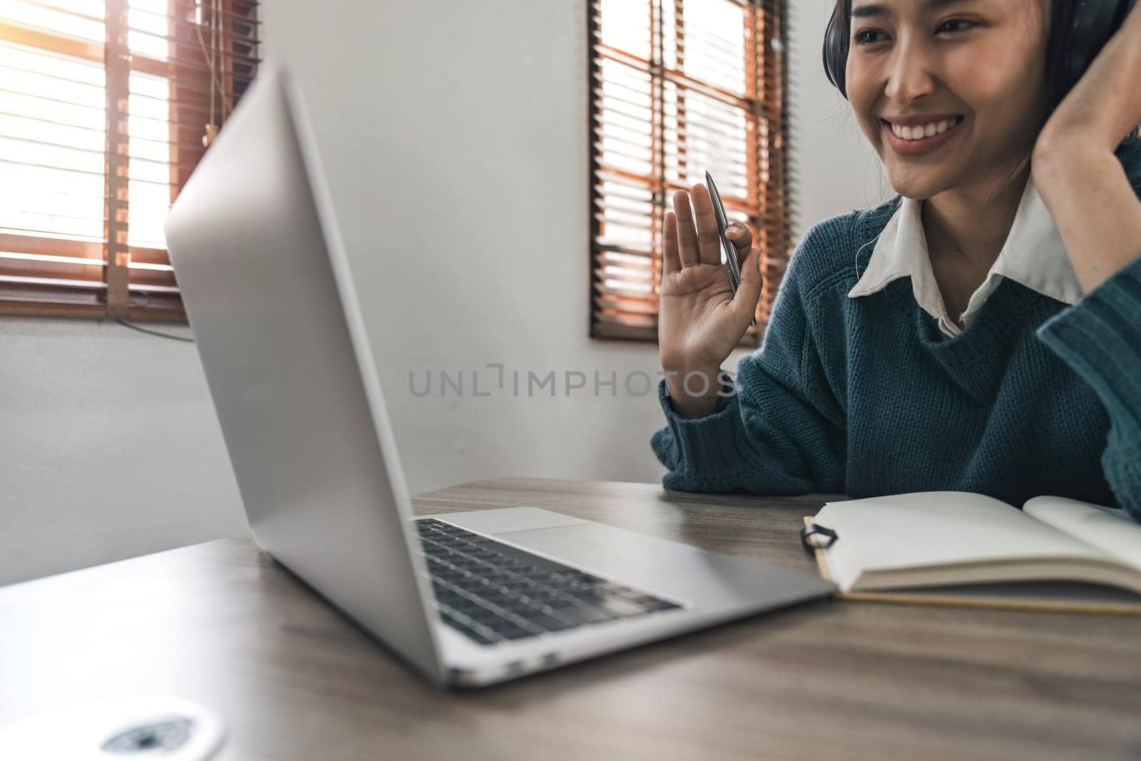 Young asian female wearing with headphones making Video Call on laptop computer. Online education concept.