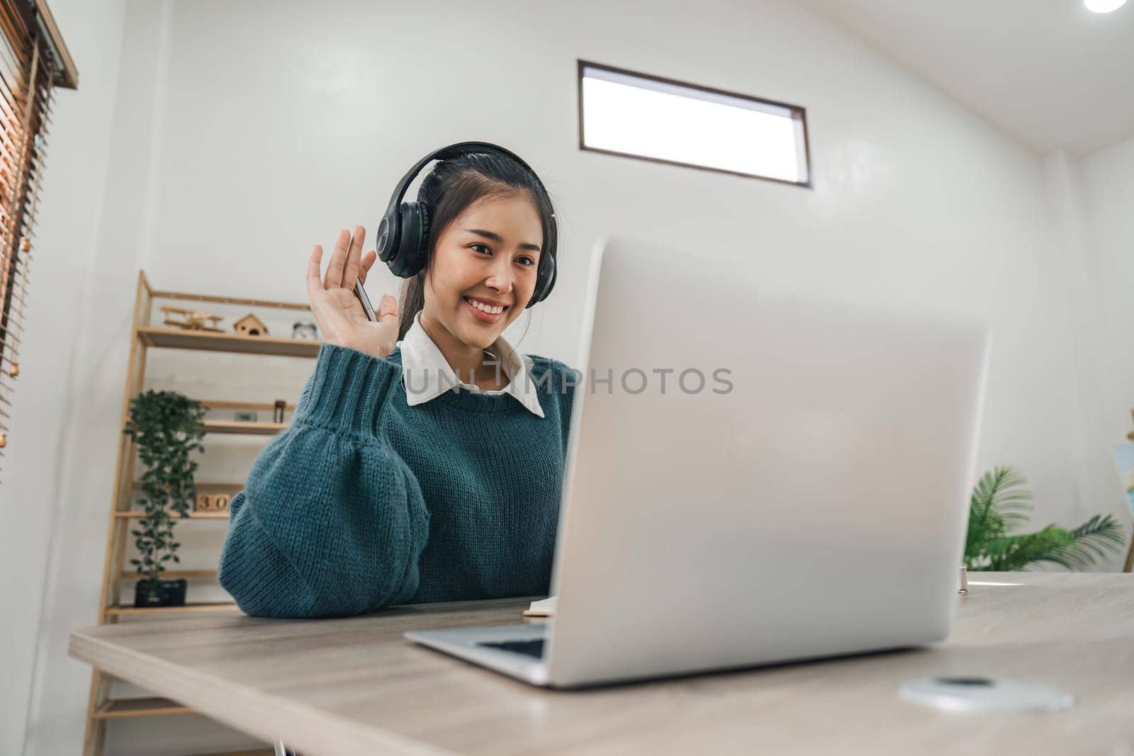 Young asian female wearing with headphones making Video Call on laptop computer. Online education concept.