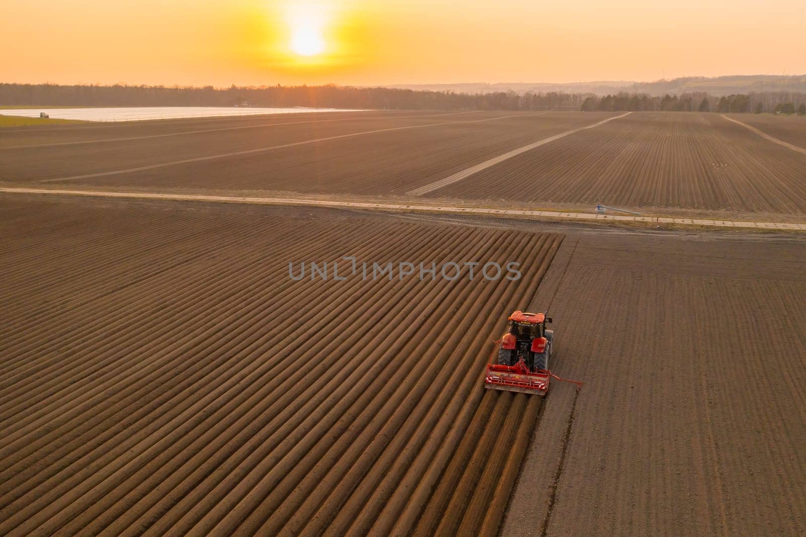 Agricultural vehicle leaves furrows using plow at sunset by vladimka