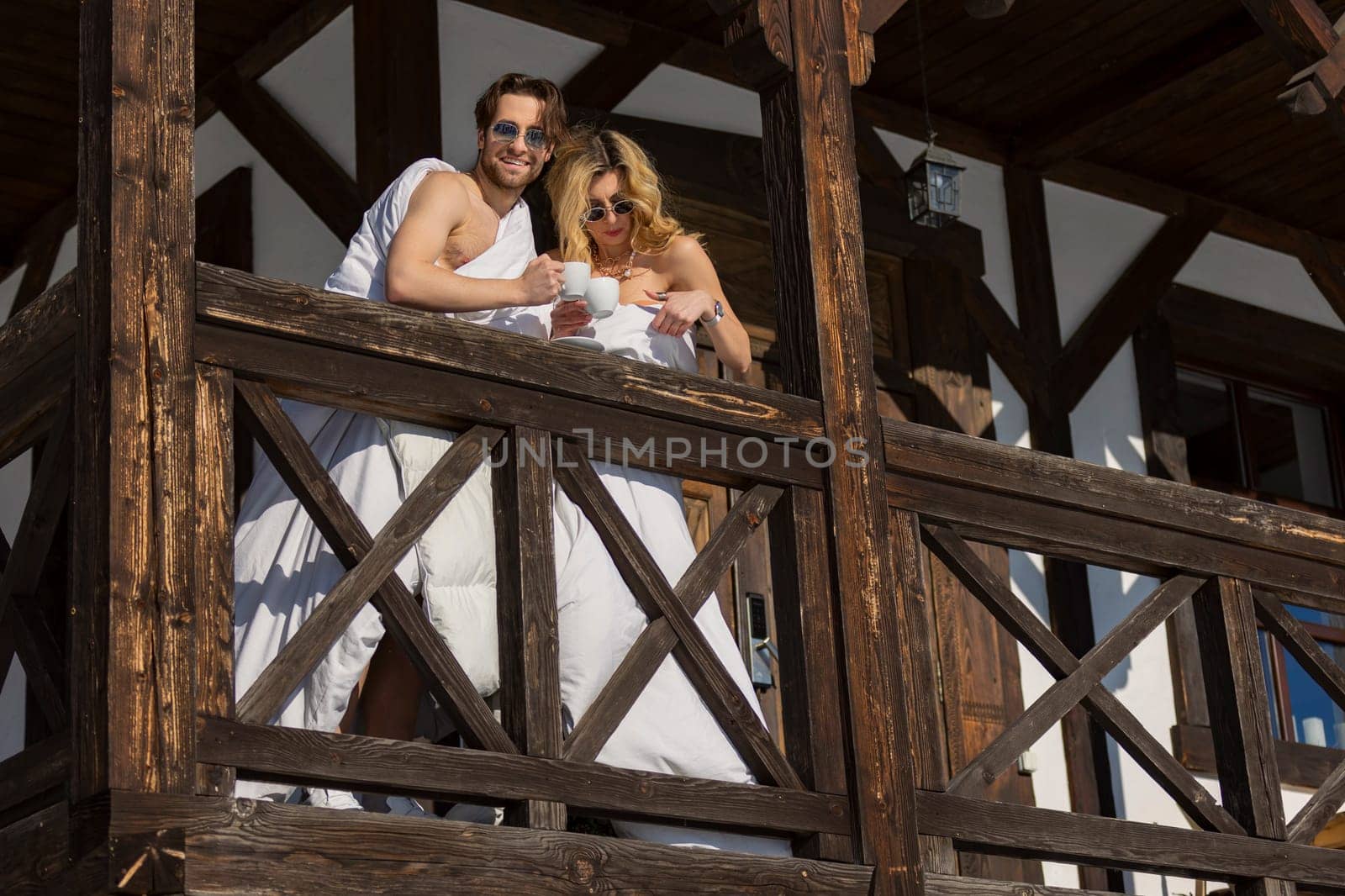 couple wrapped in blankets drinking coffee on the balcony