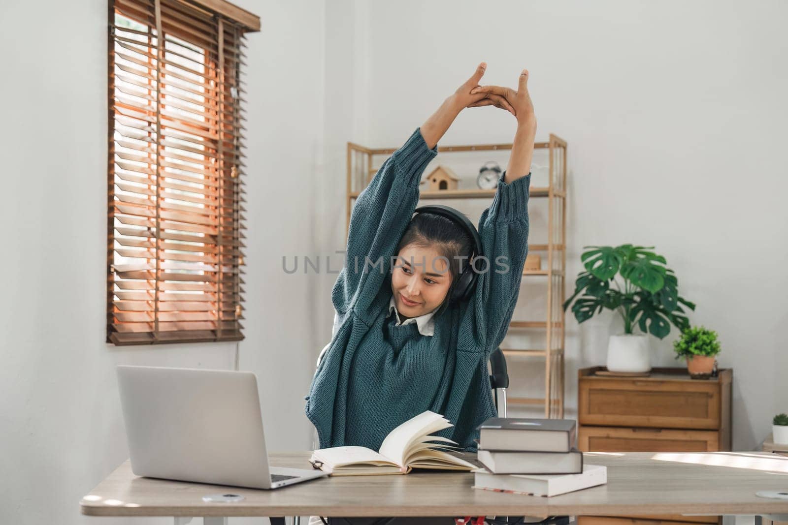 Asian young student in casual video call and doing stretch oneself from study online class. Online distance e-learning education concept by nateemee