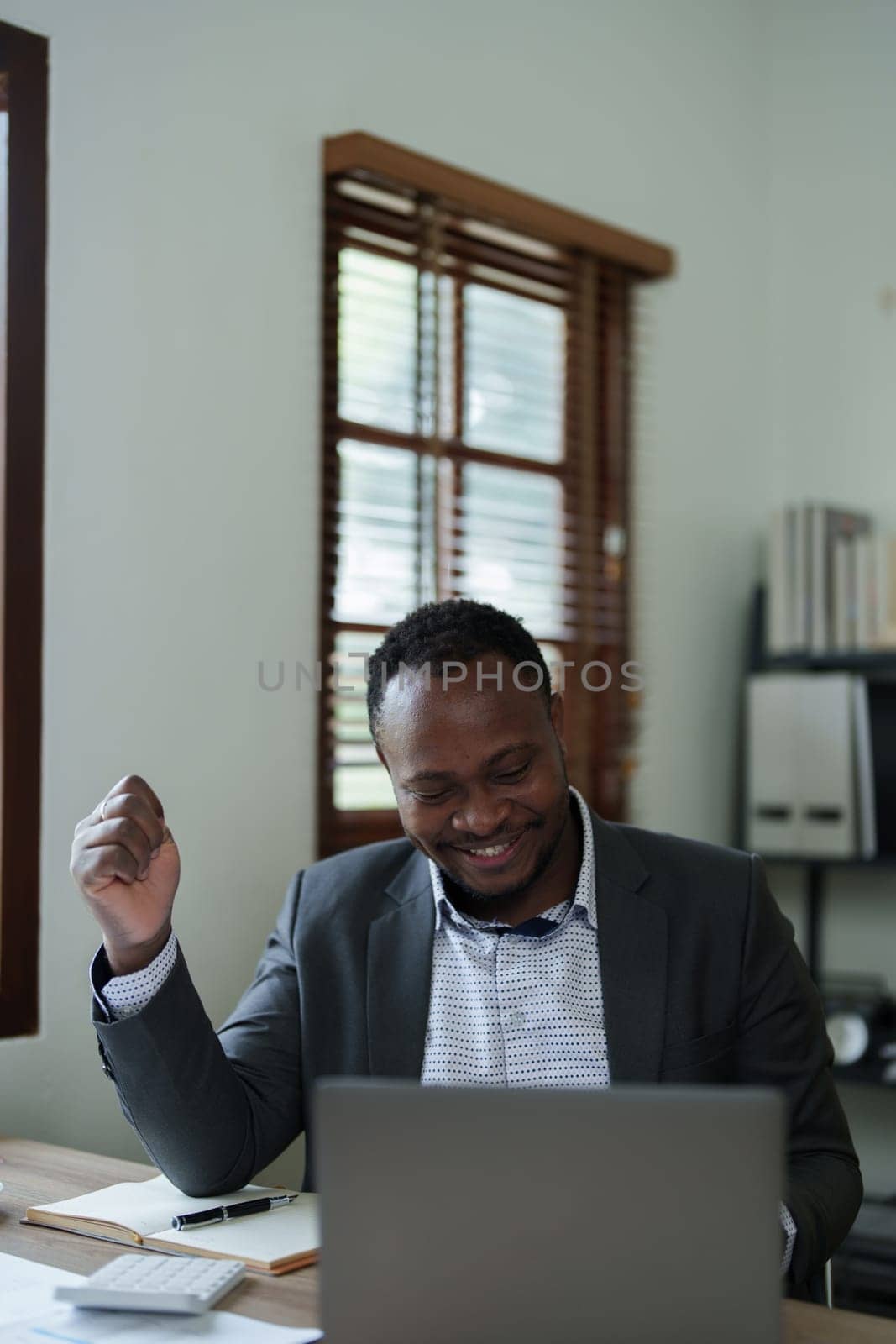middle aged man American African business man holding computer laptop with hands up in winner is gesture, Happy to be successful celebrating achievement success by Manastrong