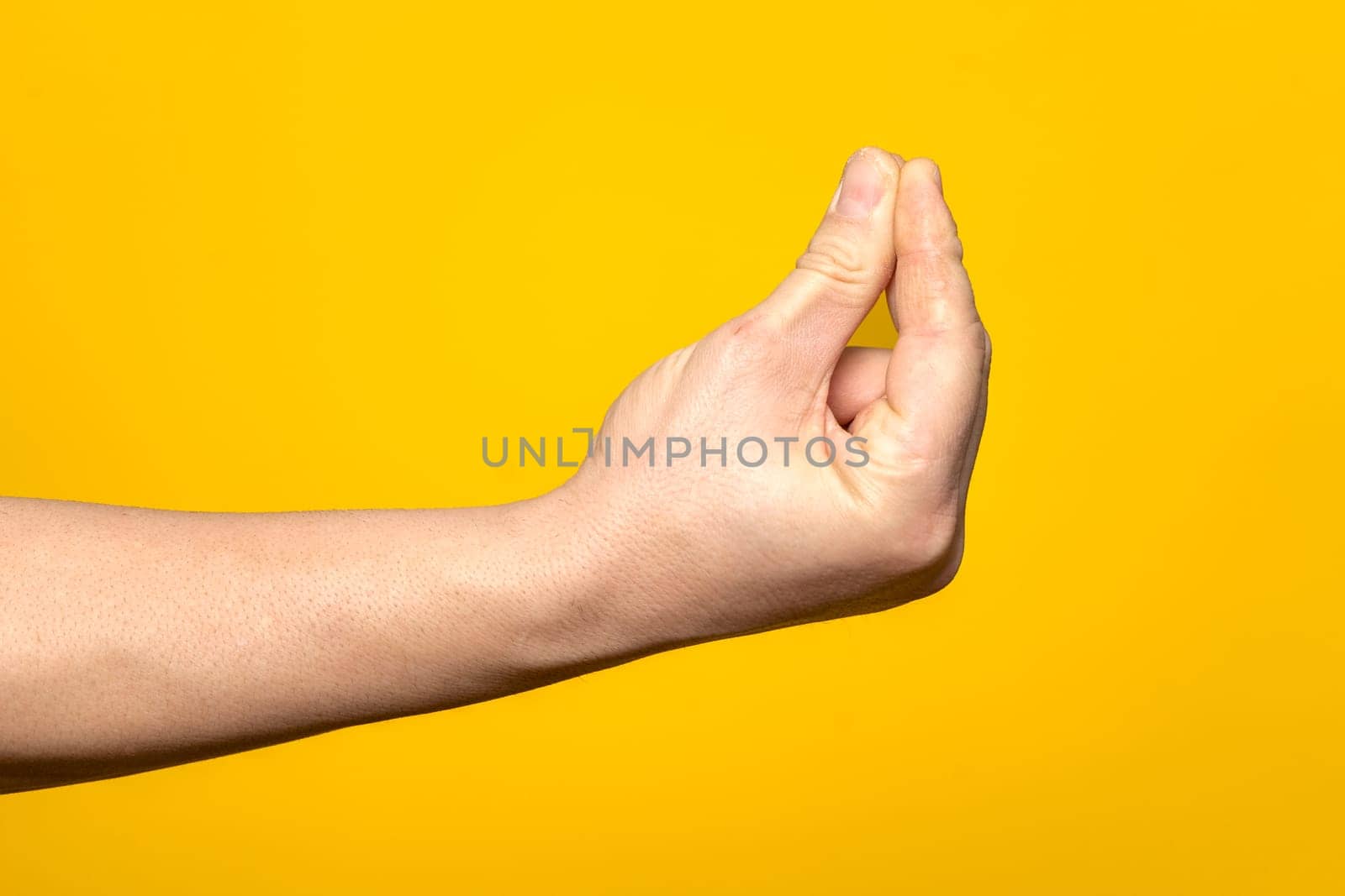 Close-up of a stout man's hand making the Italian gesture of ma que cosa face, isolated on yellow background