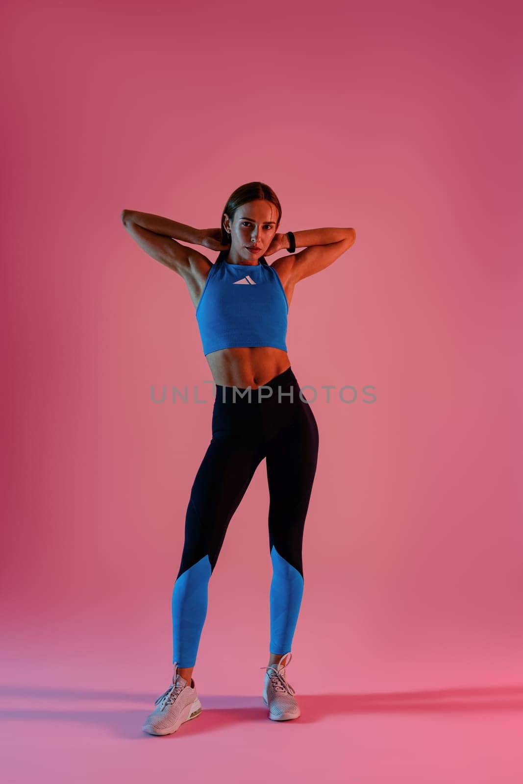 Beautiful fitness woman wearing sportswear posing over studio background and looking at camera by Yaroslav_astakhov