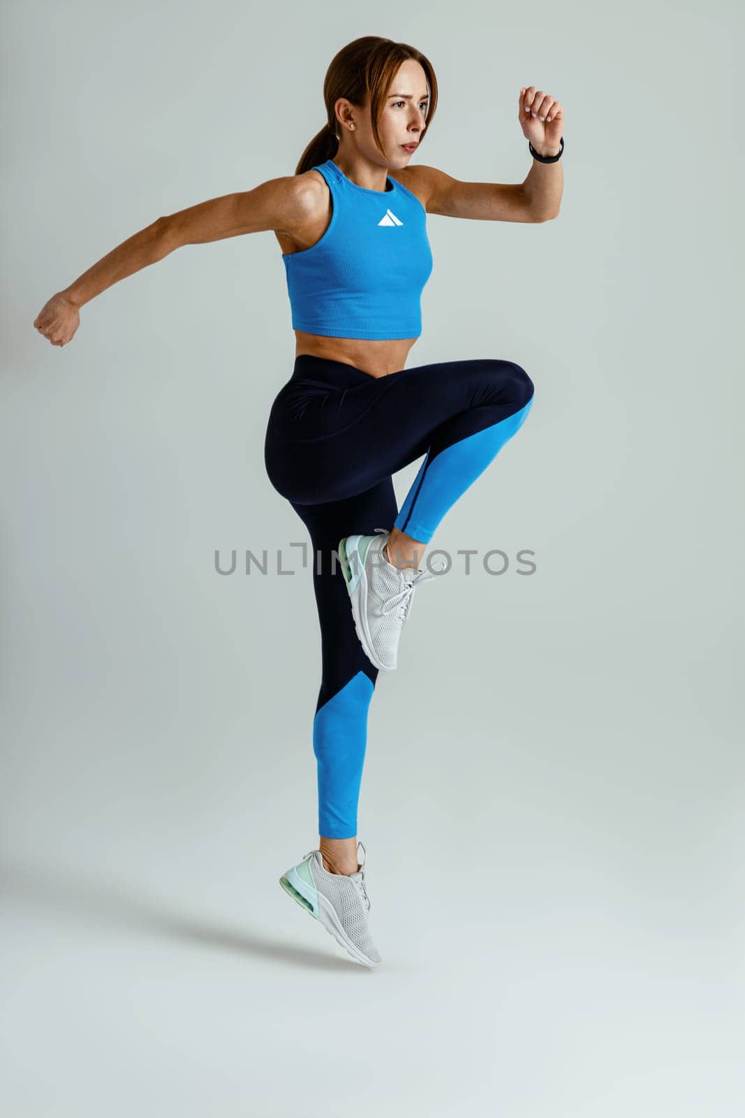 Athletic active fitness woman jumping on studio background . Dynamic movement. High quality photo