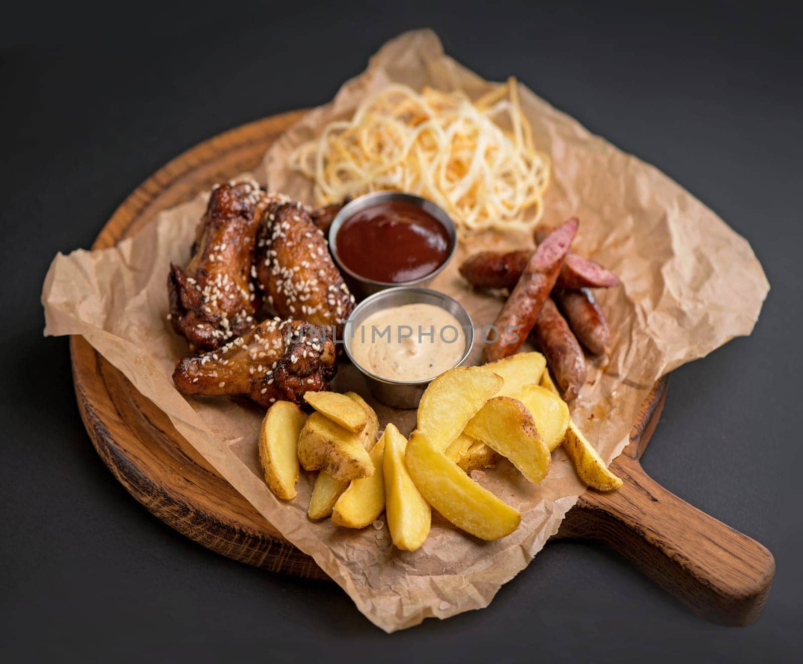 Baked chicken wings served with different sauces and lemon. Black background