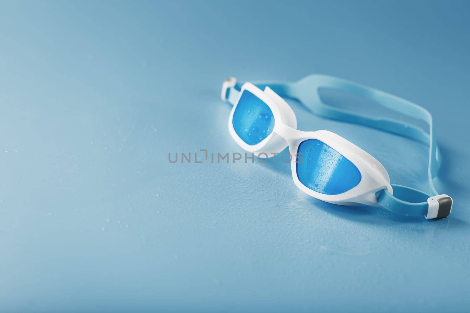 White swimming goggles on a blue background by AlexGrec