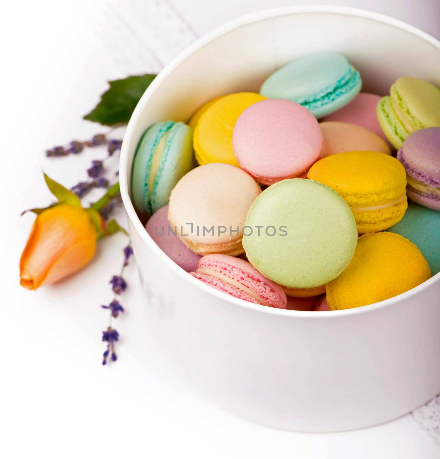 Many delicious colorful macarons in box on white background by aprilphoto