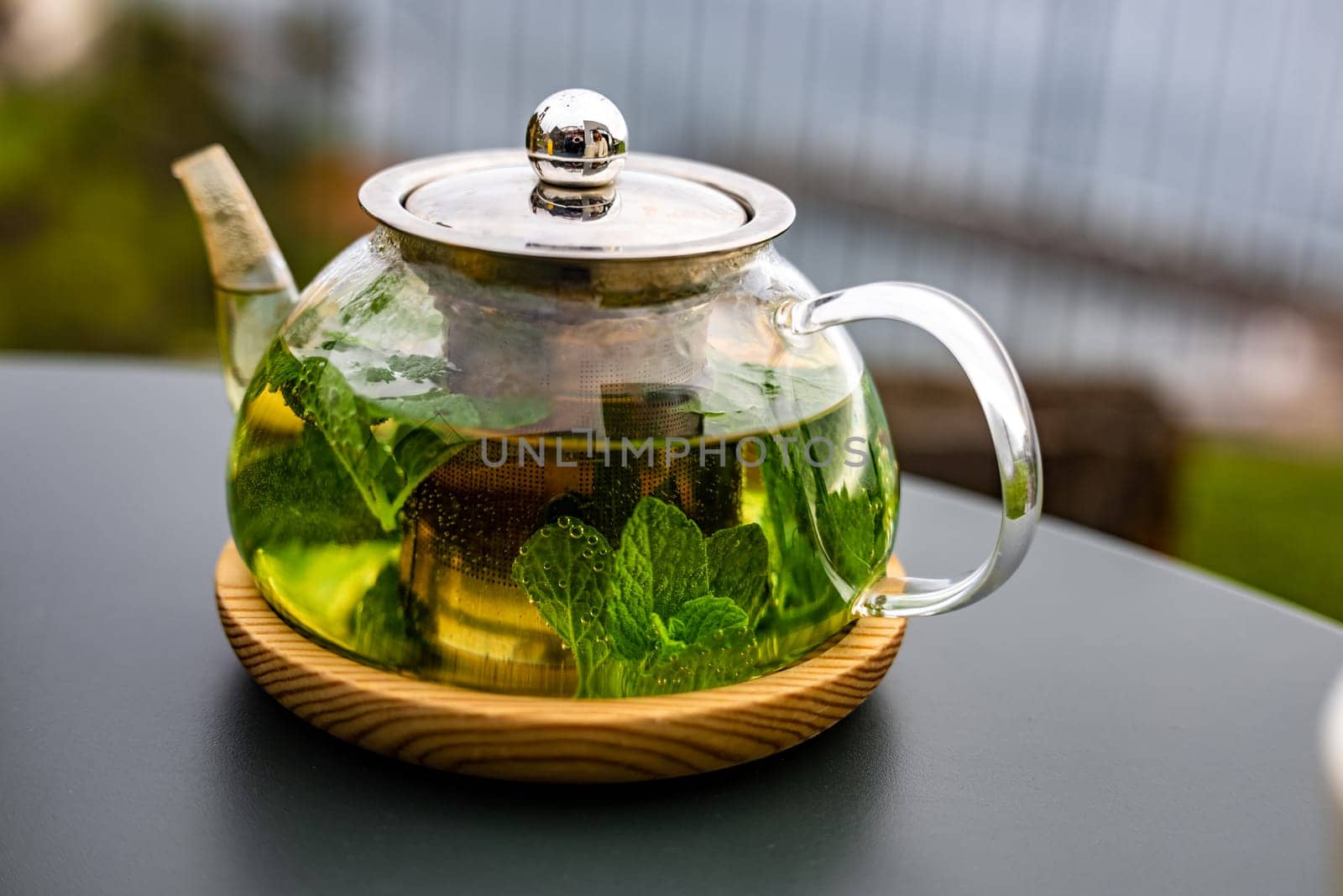 A steaming teapot of fragrant mint tea sits on a table outdoors, the perfect accompaniment to a healthy meal.