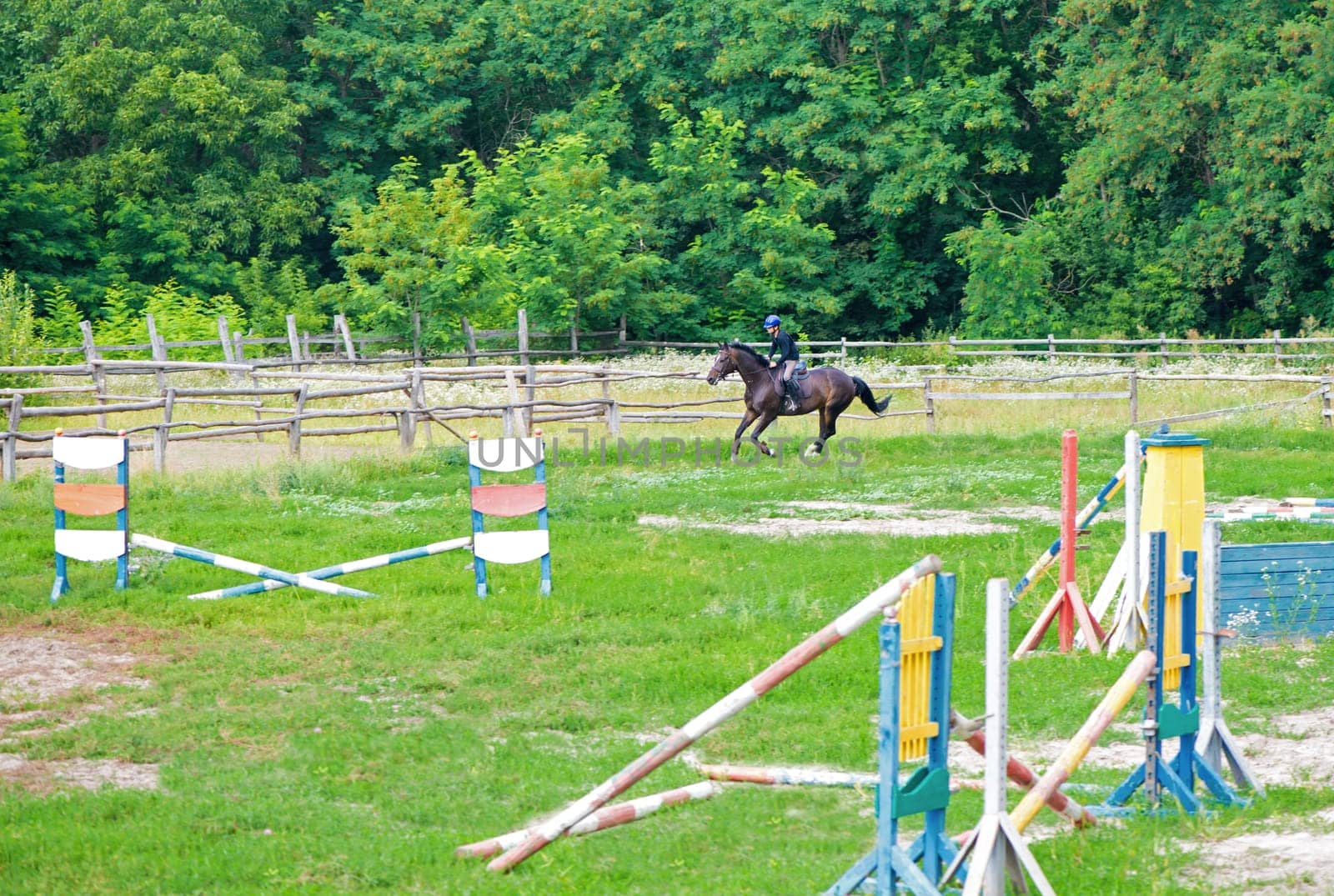 Young rider on horse jumping over obstacle on her course in competition