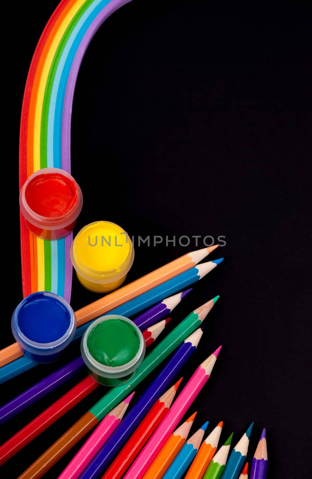 Top view of a blank notebook, a sheet of colored paper, quilling paper, drawing supplies, brushes and colored pencils on a black background. The process of creation, creativity. Copy space by aprilphoto