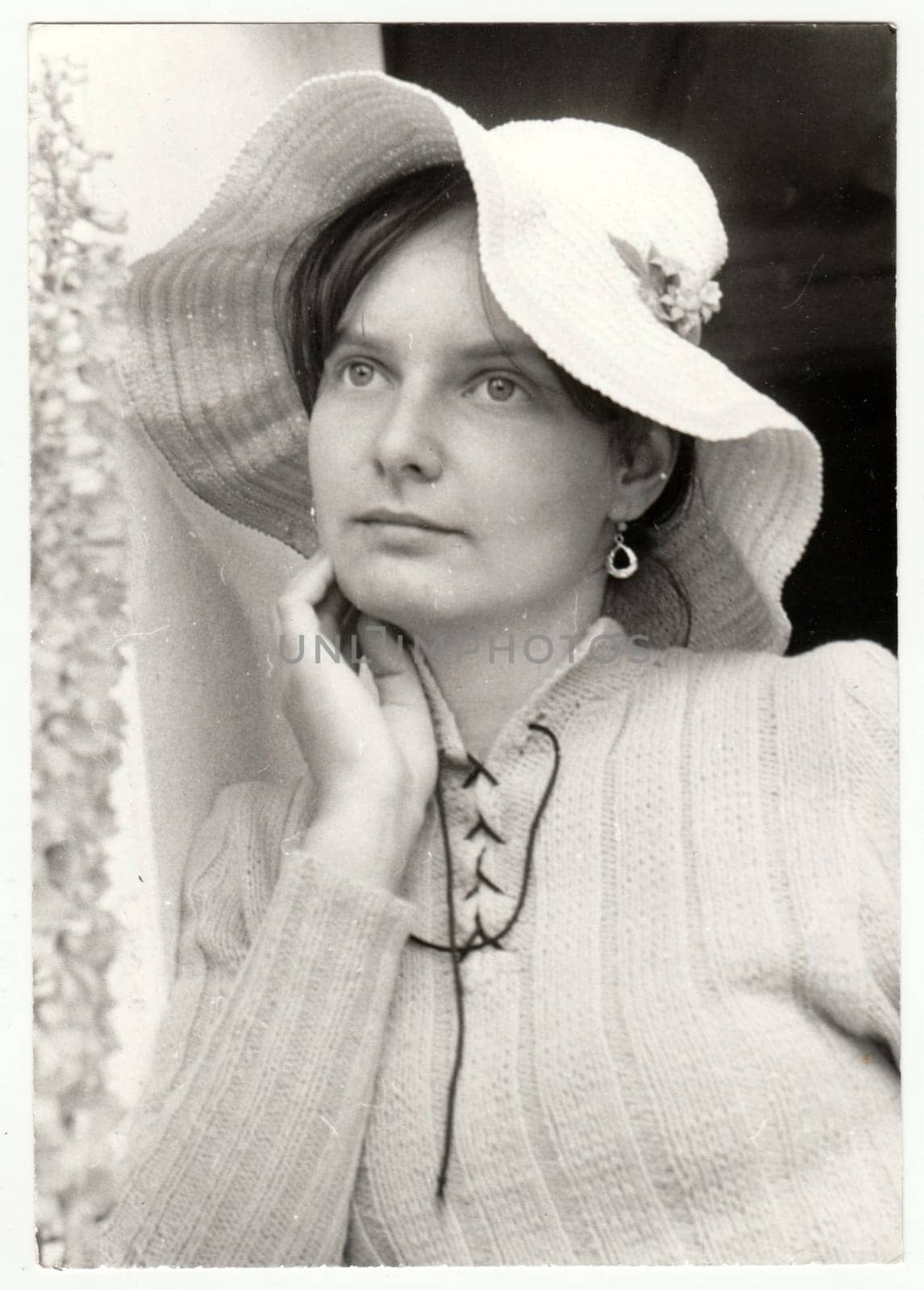 THE CZECHOSLOVAK SOCIALIST REPUBLIC - SEPTEMBER 1982: Vintage photo shows a teenager girl poses outdoors. She wears a romantic woman hat. Retro black and white photography. Circa 1980.