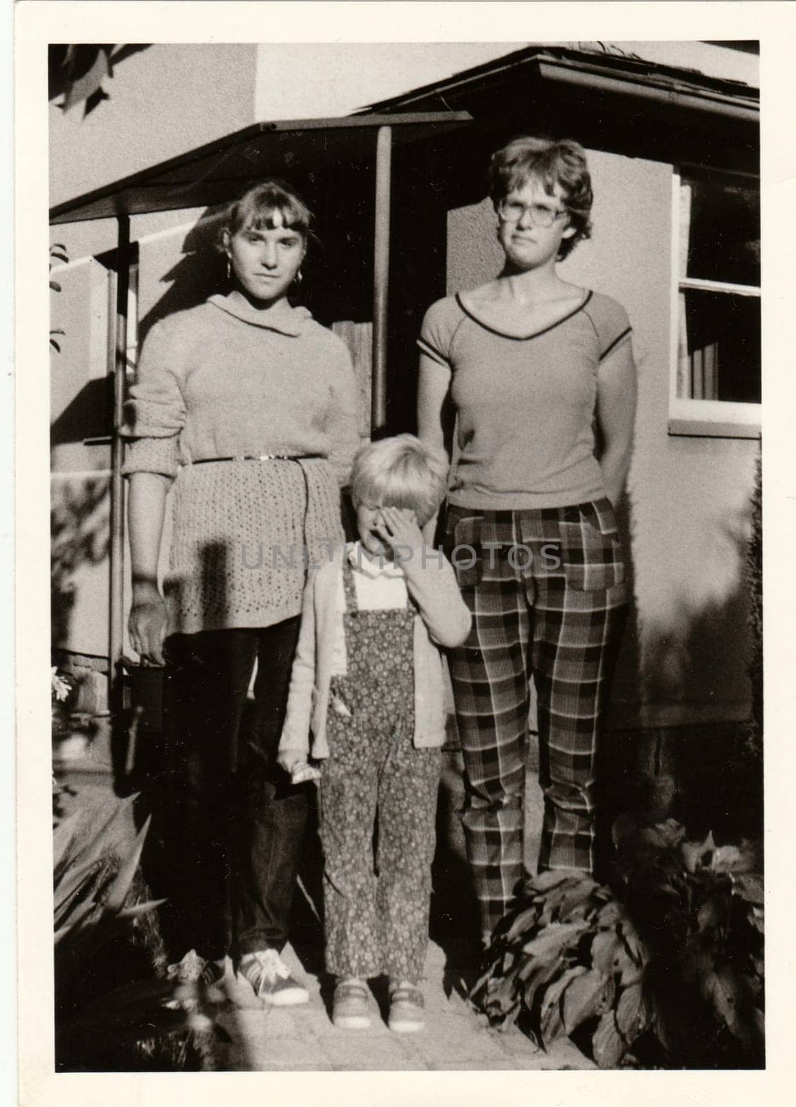 Vintage photo shows young girls and child in front of country house. Retro black and white photography. Circa 1980. by roman_nerud