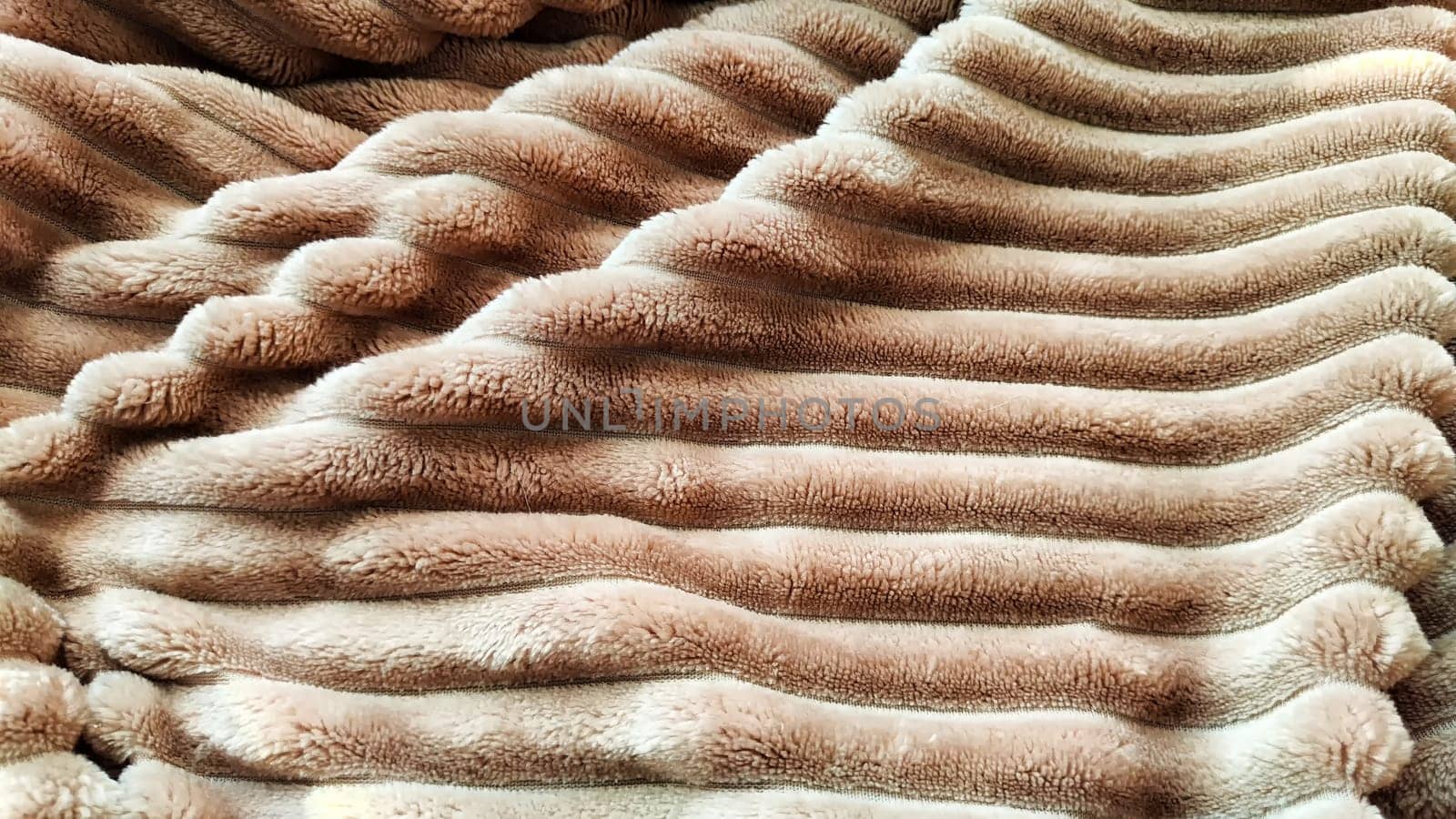 Closeup photo of soft, fluffy sleeping beige blanket or plaid. Crumpled fabric. Abstrack background and texture with frame. Partial focus