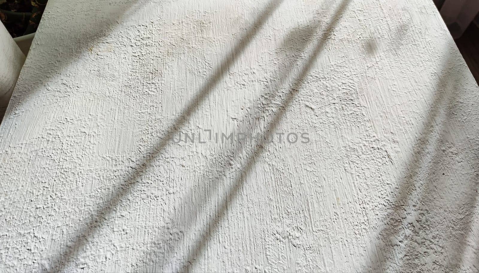 Abstract pattern with stripes and lines of shadow and light from sun on textured white whitewash, plaster, paint. Background and texture