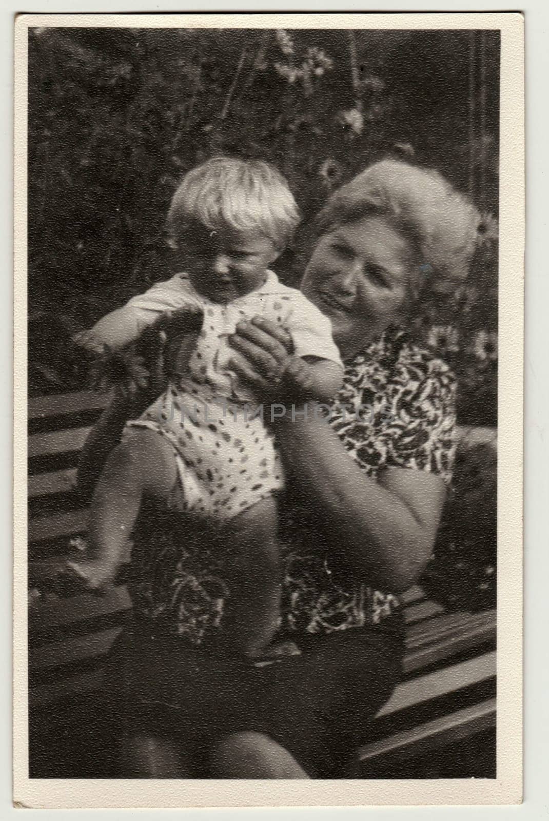 Vintage photo shows grandmother holds a small baby. Retro black and white photography. Circa 1980. by roman_nerud